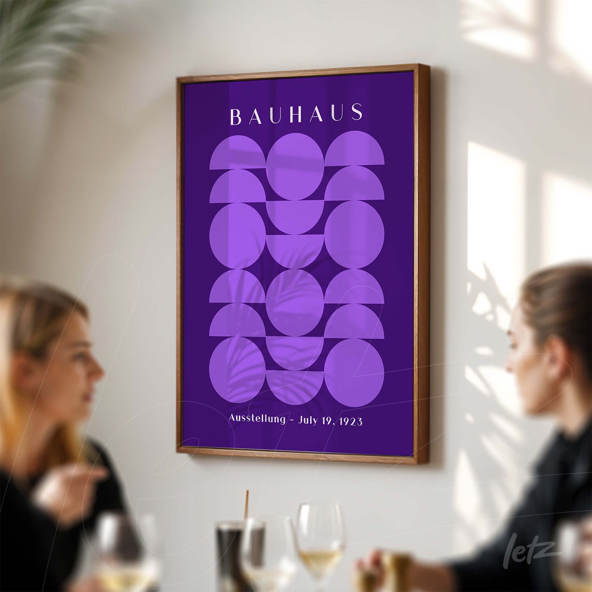poster print featuring purple geometric design in wooden frame, displayed in a social setting with two people in the background
