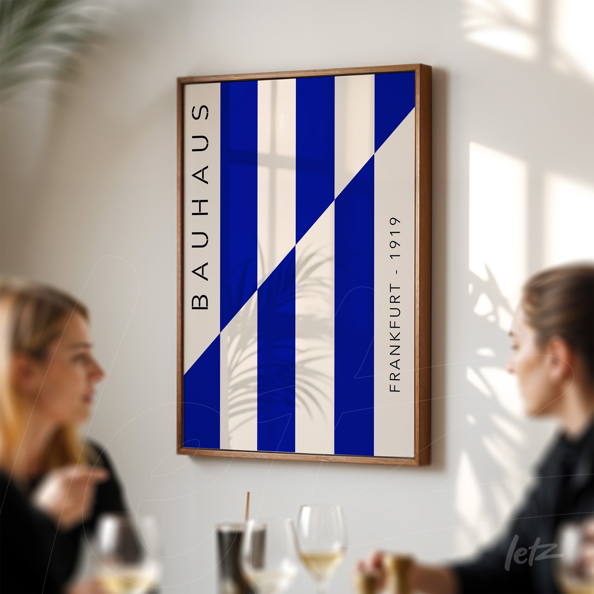 modern art with blue and white stripes in light wooden frame, displayed on wall with two people chatting in the background