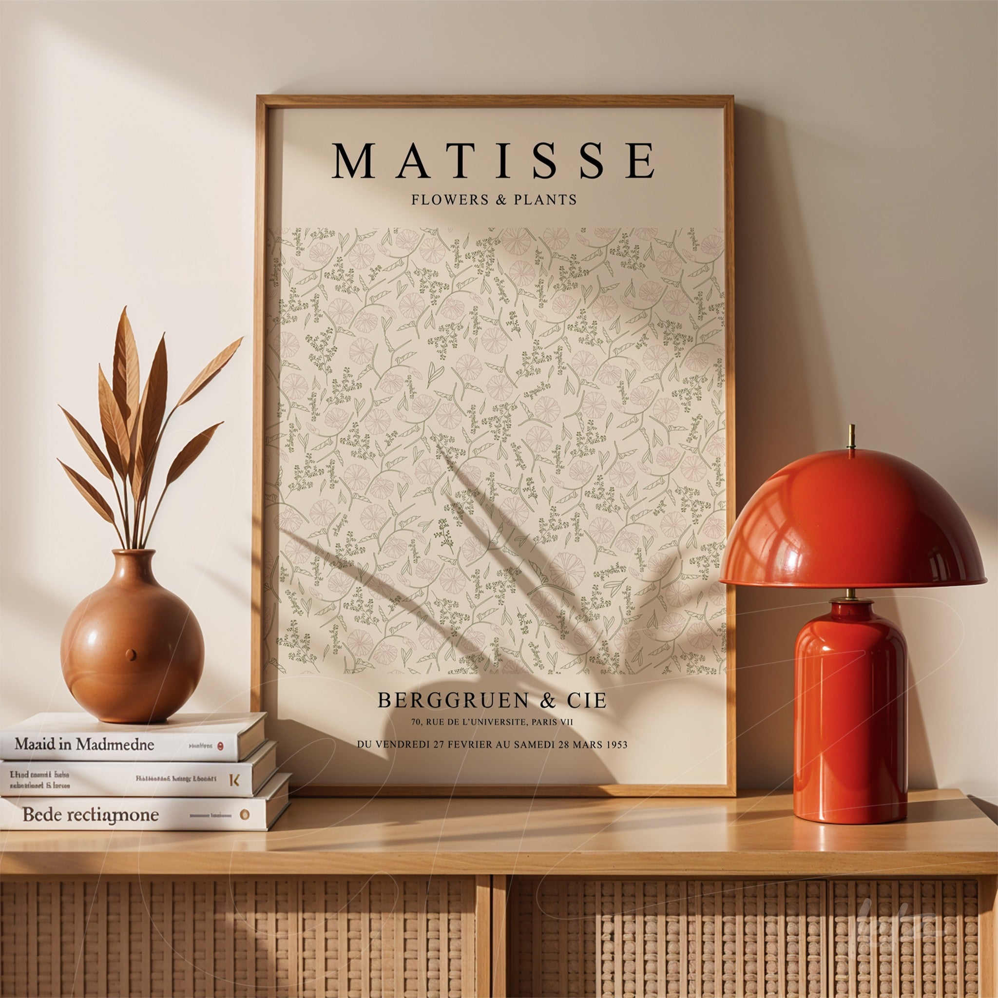 framed wall art of matisse flowers and plants with light wood frame displayed on a table with a vase and red lamp