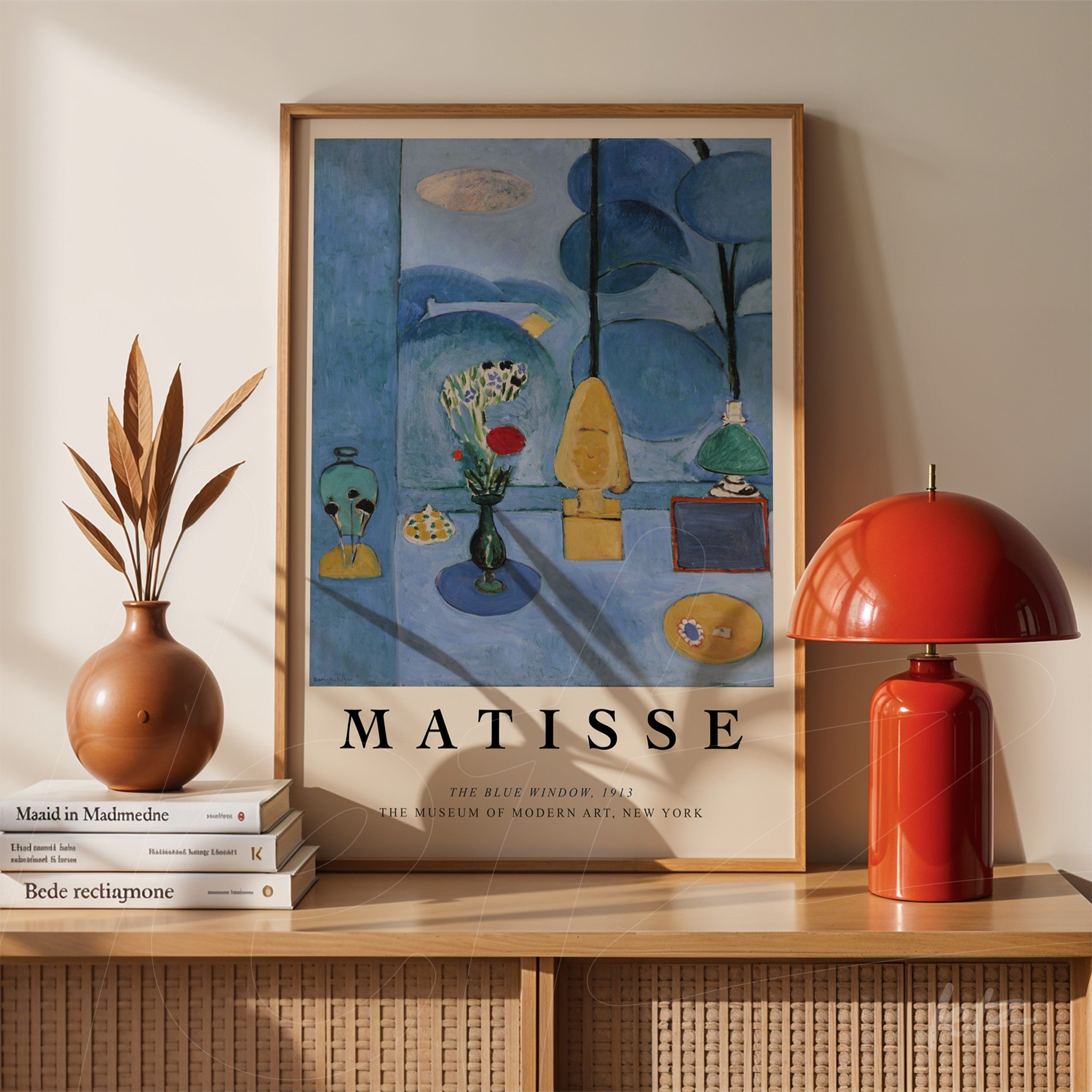 framed artwork by Matisse displayed on a table next to a terracotta vase and a red lamp