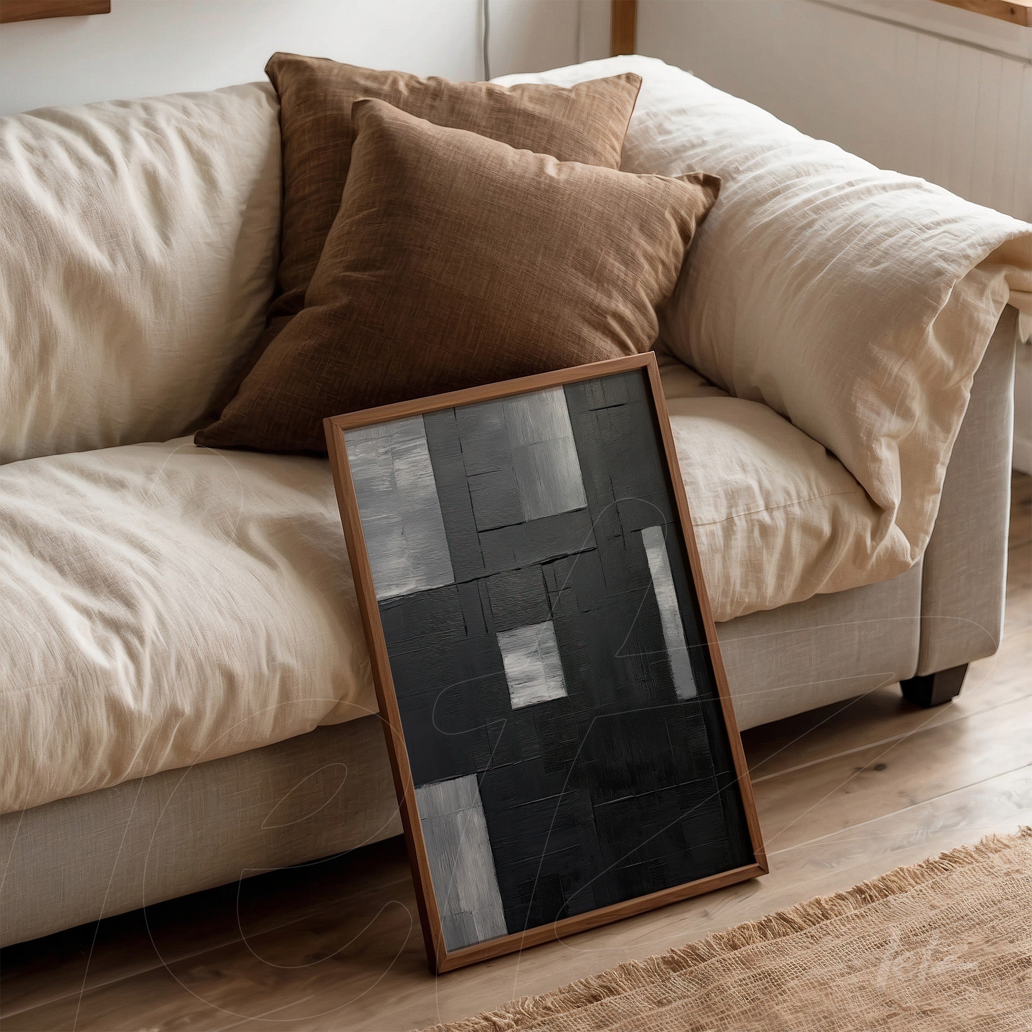 contemporary wall art in shades of black and gray, leaning against a light sofa with brown cushions
