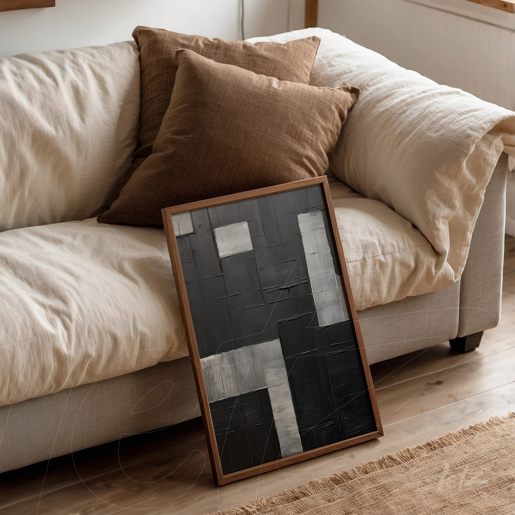 abstract wall art in black and gray tones with textured elements leaning against a light sofa, featuring a natural wood frame