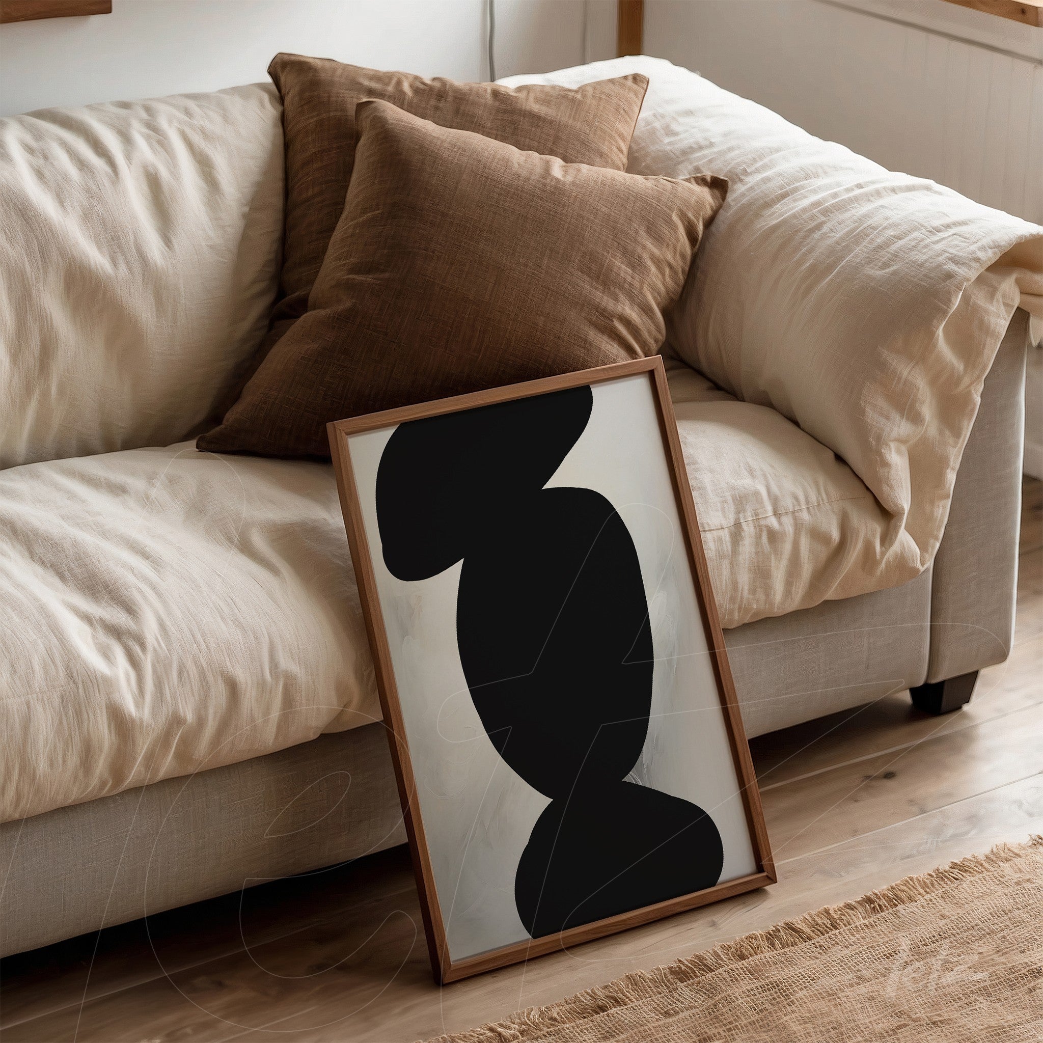 minimalist artwork featuring abstract black shapes, leaning against a sofa with brown cushions