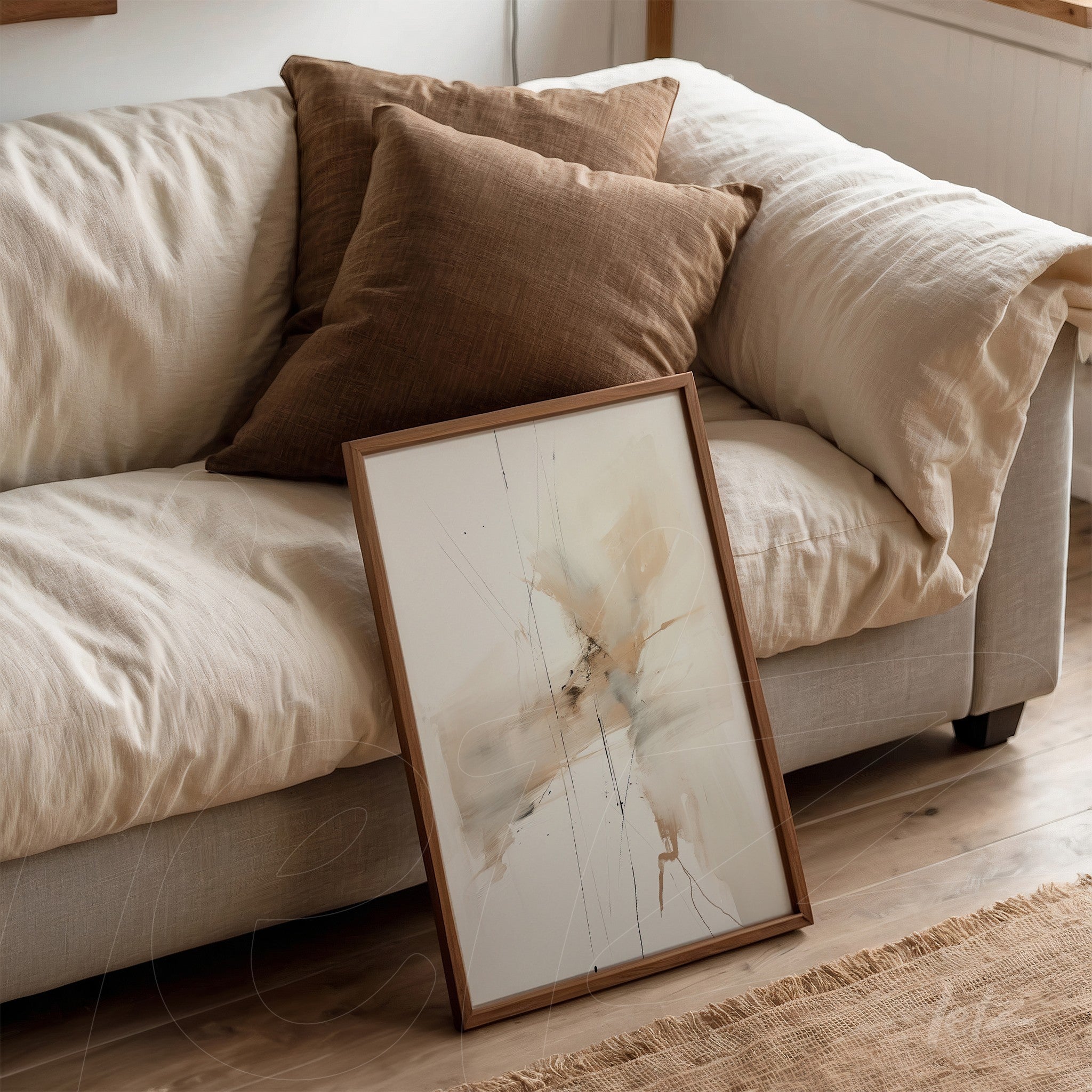abstract art piece in earthy tones leaning beside cushions on a light sofa with a light wood frame