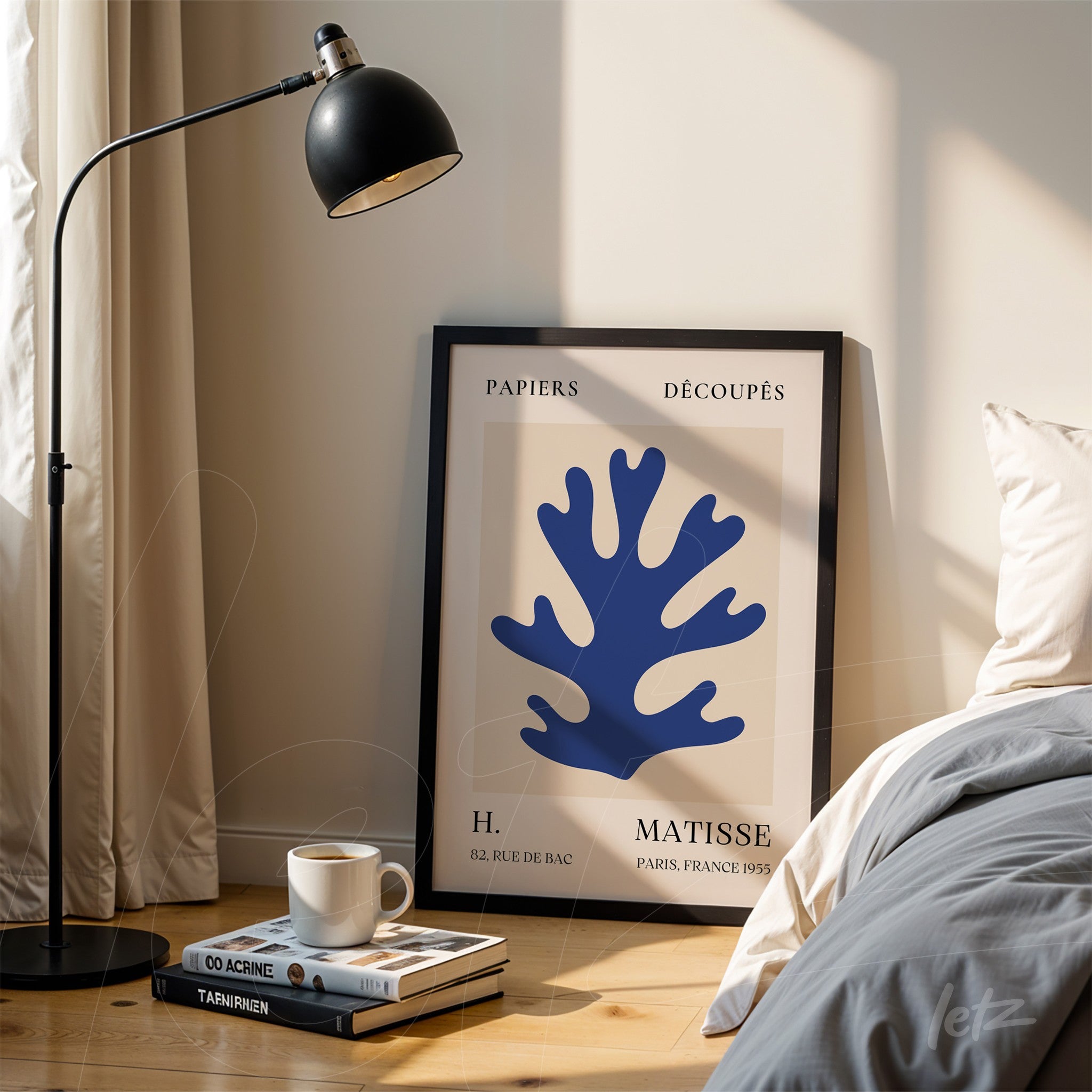framed modern art print of blue coral in black frame, leaning next to a bed with bedside table