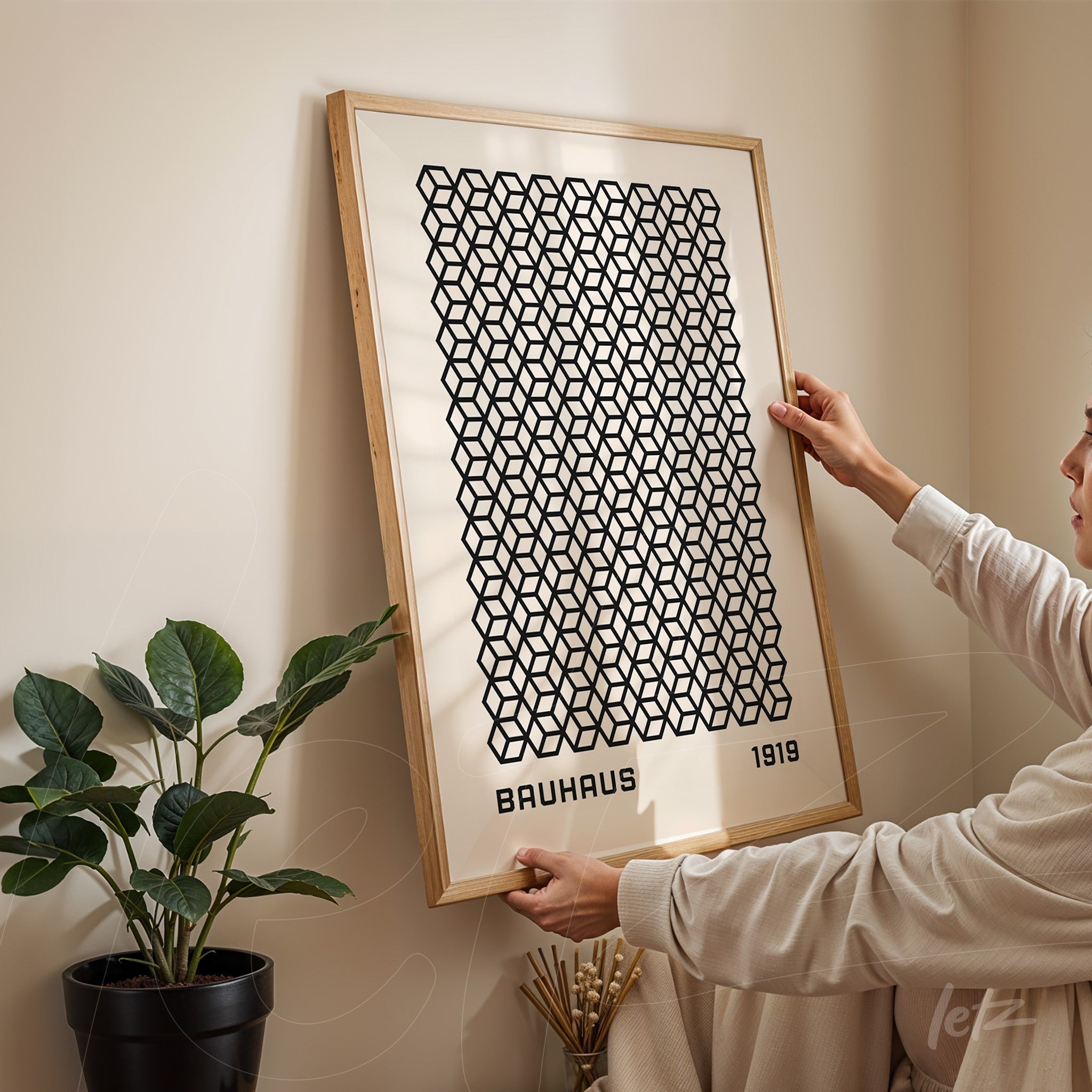 poster print with black geometric pattern in light wood frame, displayed indoors with a plant beside