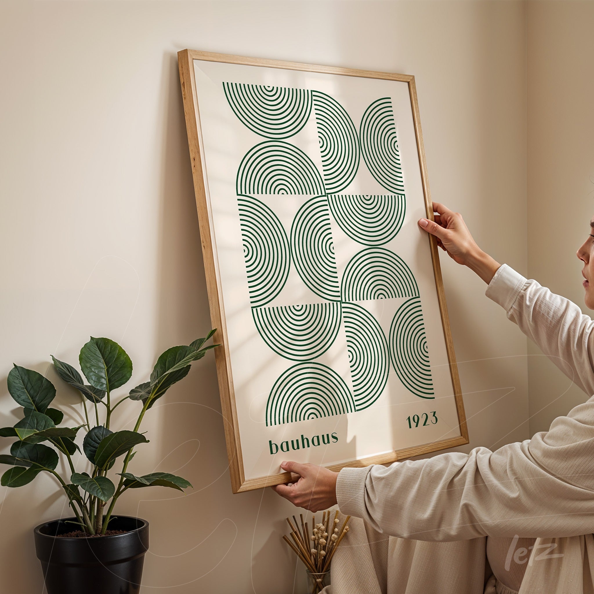 poster print in bauhaus style with green geometric shapes and light wooden frame being hung on a neutral wall