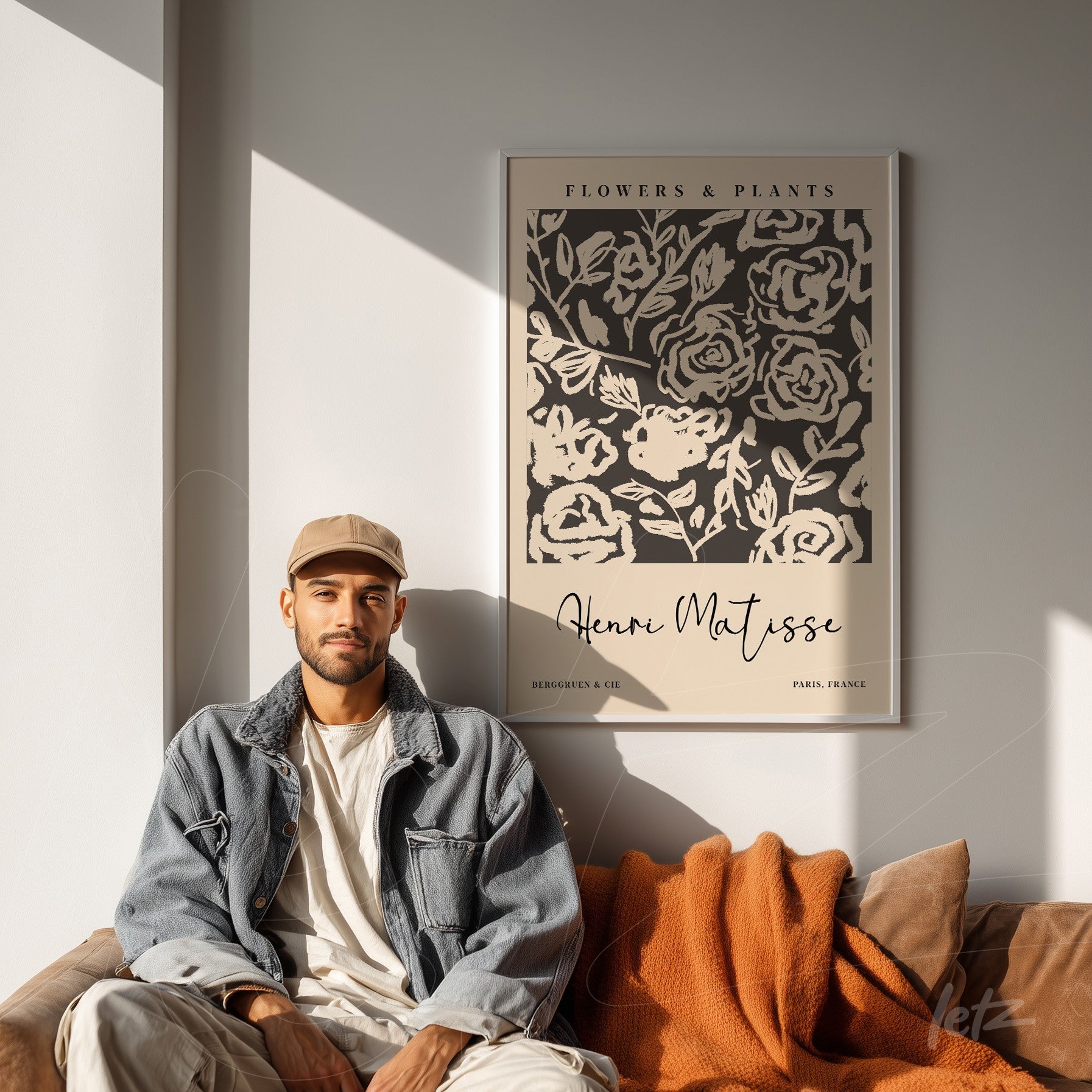 decorative wall art featuring flower and plant design in classic frame, displayed on light wall in a room with brown sofa and orange blanket