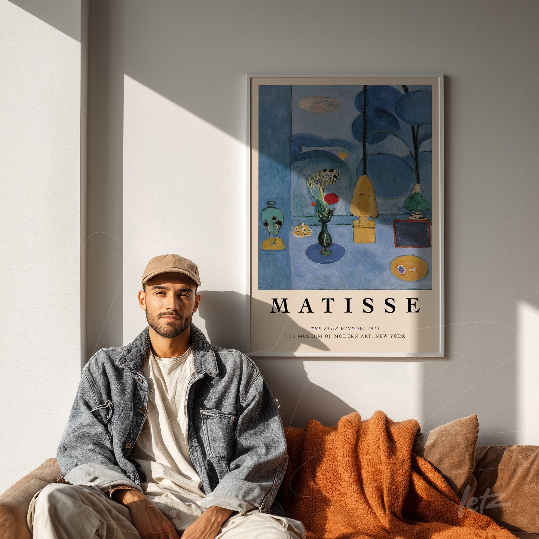 framed modern art print on the wall featuring green vases, flowers, and a colorful Matisse painting displayed in a cozy setting with a brown sofa and an orange throw blanket