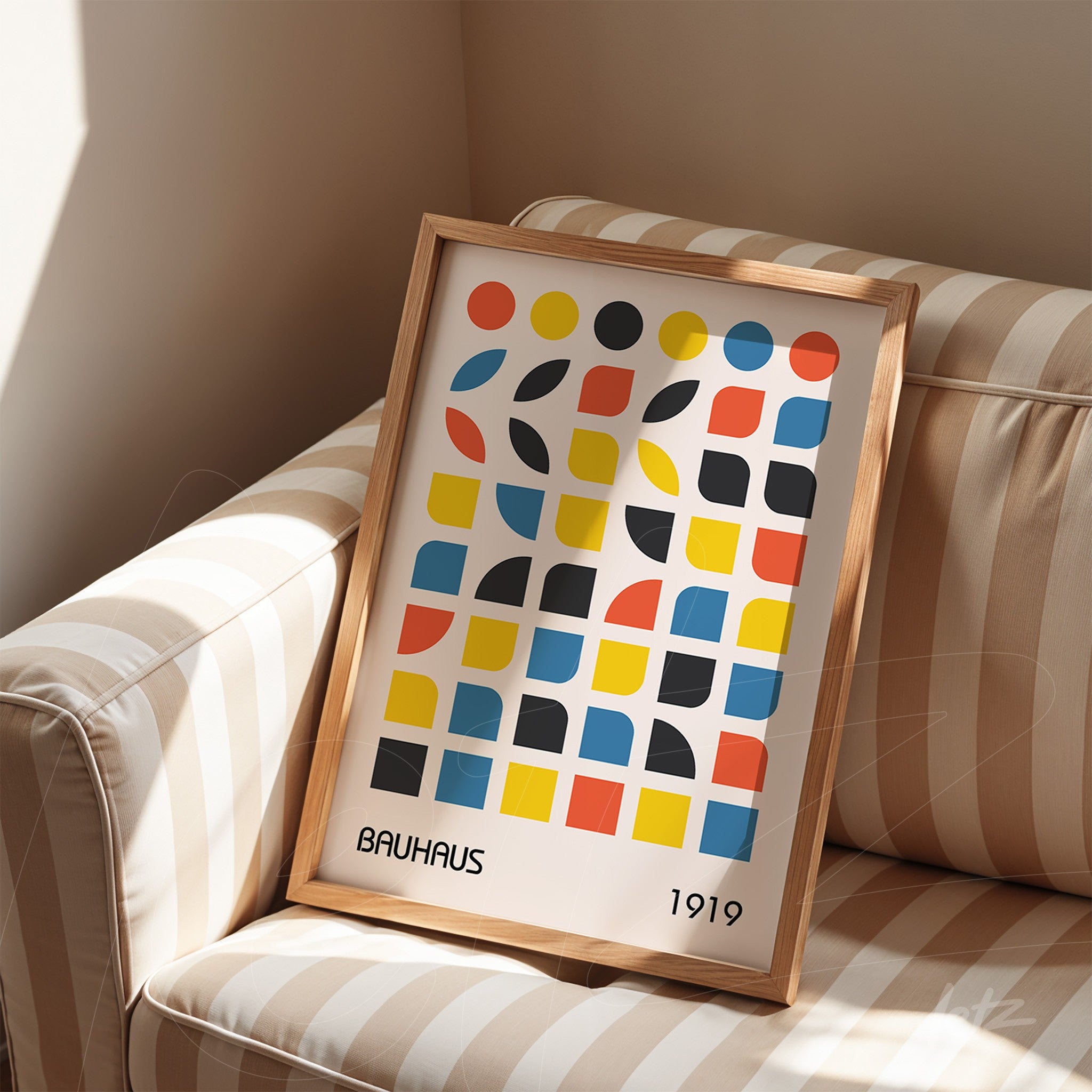 modern geometric art print in natural wood frame resting on a striped sofa