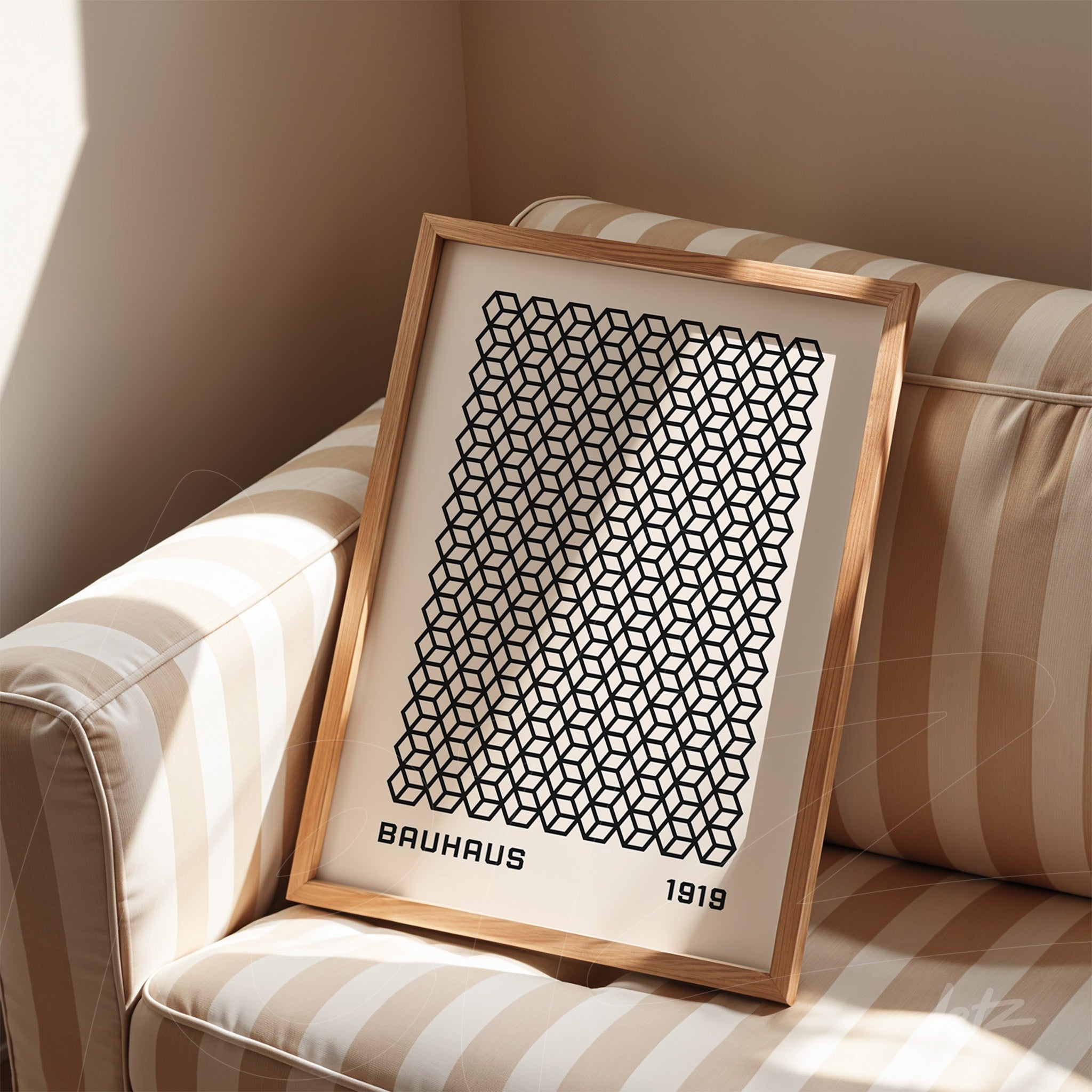 poster print featuring black geometric pattern in light wood frame resting on striped beige sofa