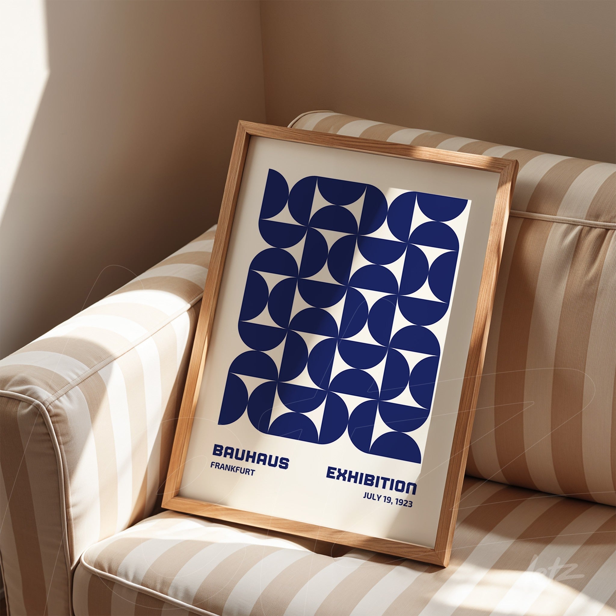 poster print with navy blue geometric design in natural wood frame, propped on striped sofa