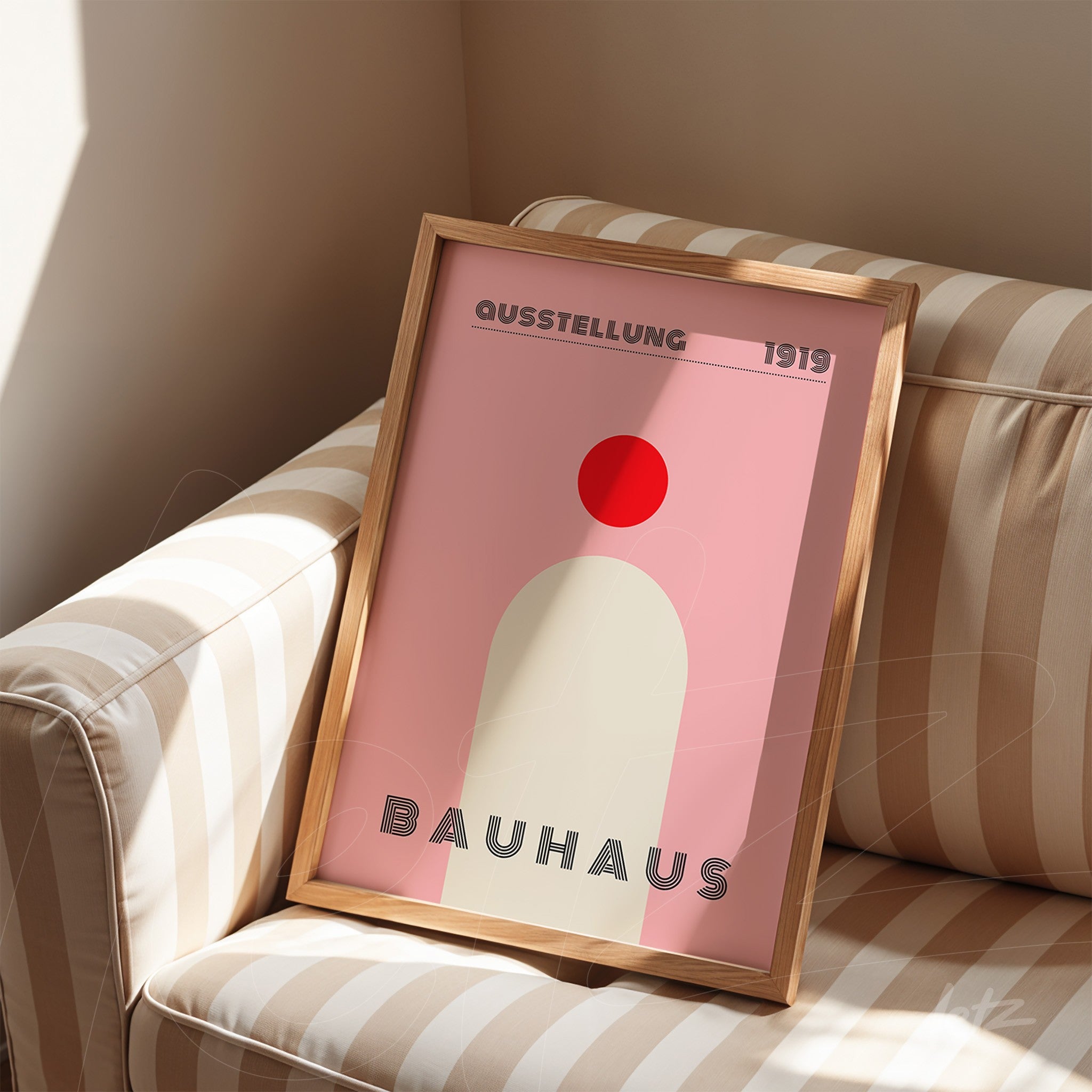 poster print with geometric Bauhaus style design in light wood frame, displayed on striped sofa