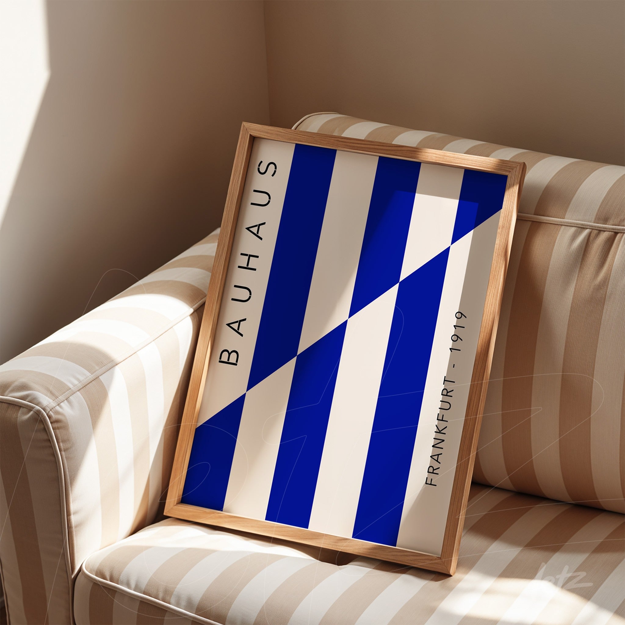 framed geometric design art in blue and white with lateral text resting on striped sofa