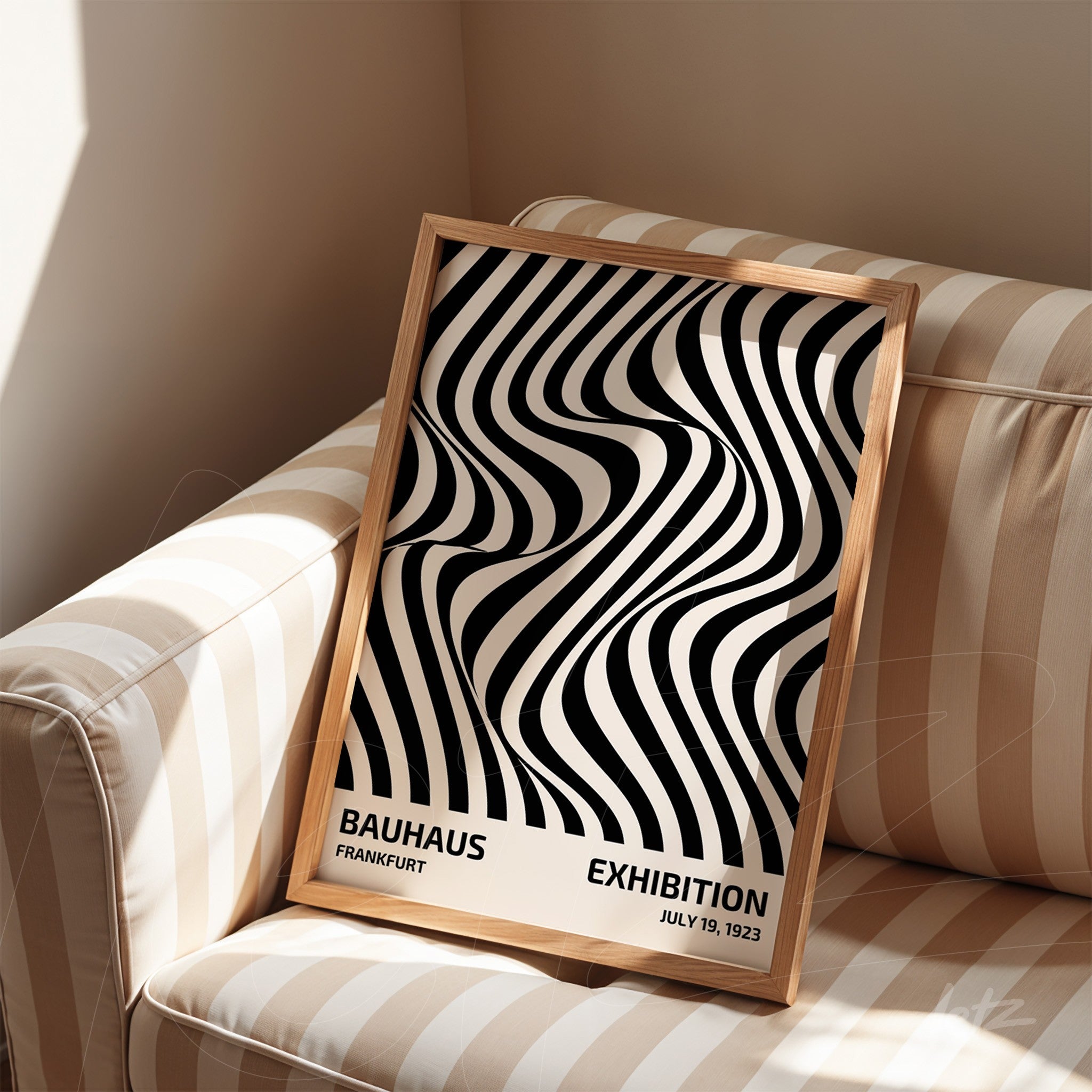 abstract black and white poster with light wooden frame, placed on striped sofa
