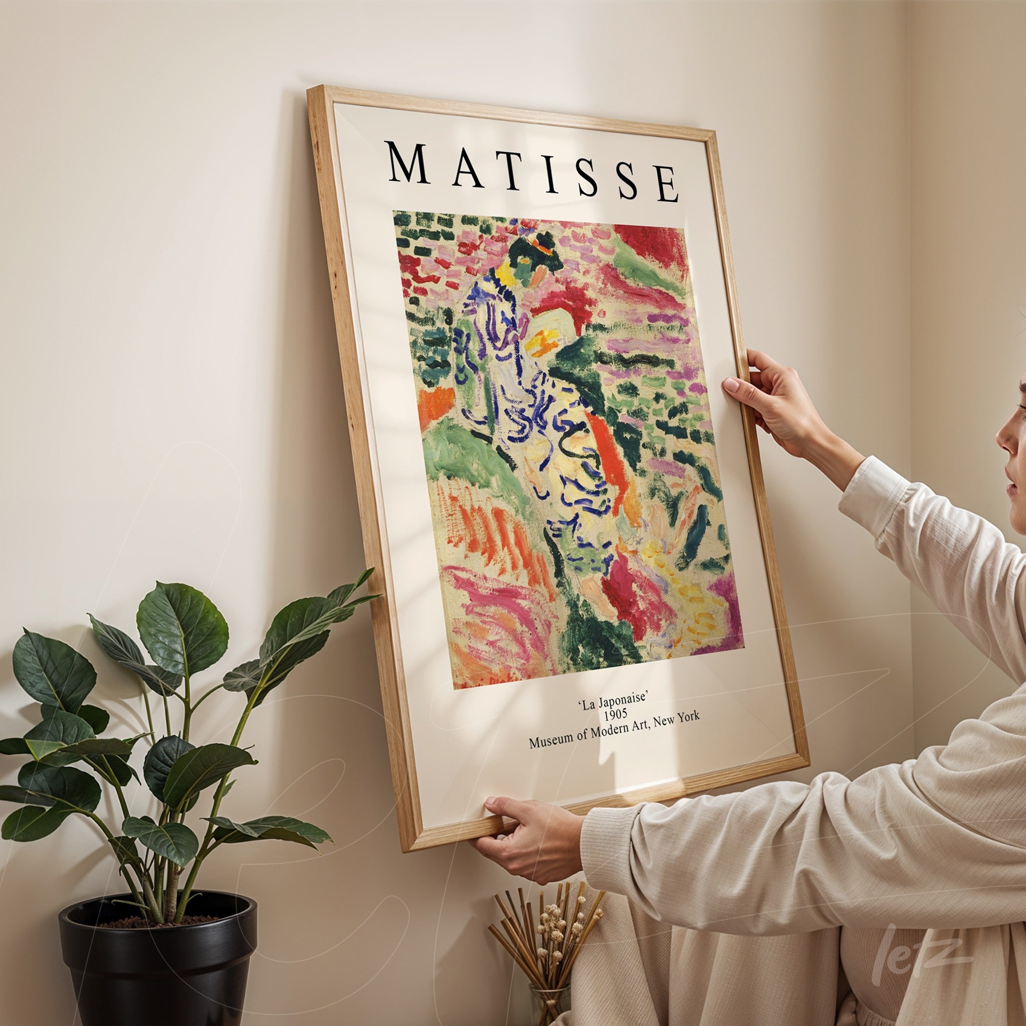 framed artwork by Matisse titled 'La Jalousie' held by a person in a cozy indoor setting with a potted plant in the background