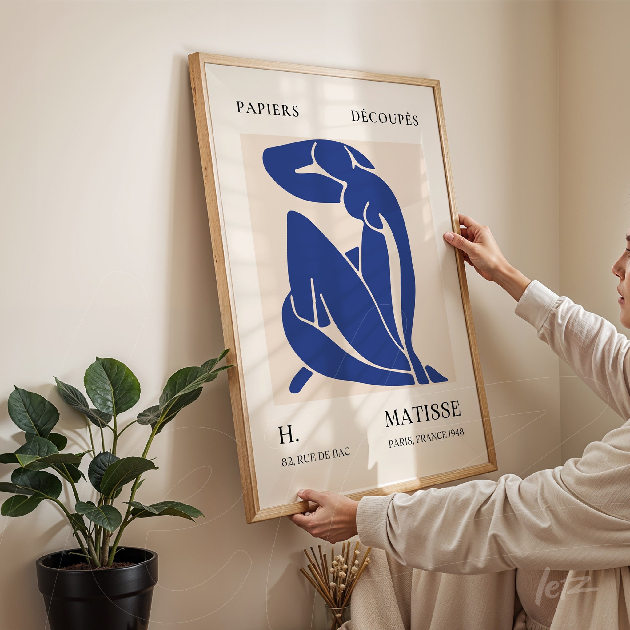 modern artwork featuring a blue silhouette of a female figure in a light wood frame displayed against a beige wall
