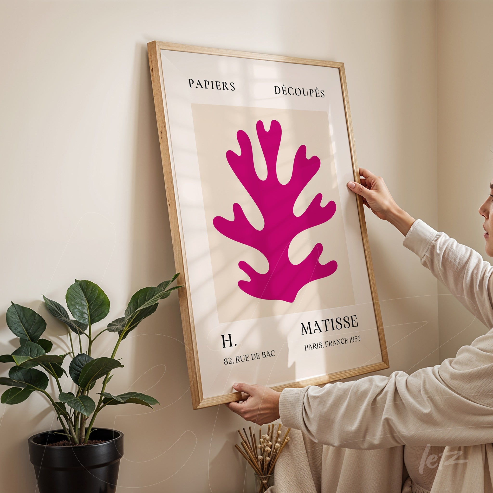 framed contemporary art featuring a pink coral shape displayed in an indoor setting with a plant in the background