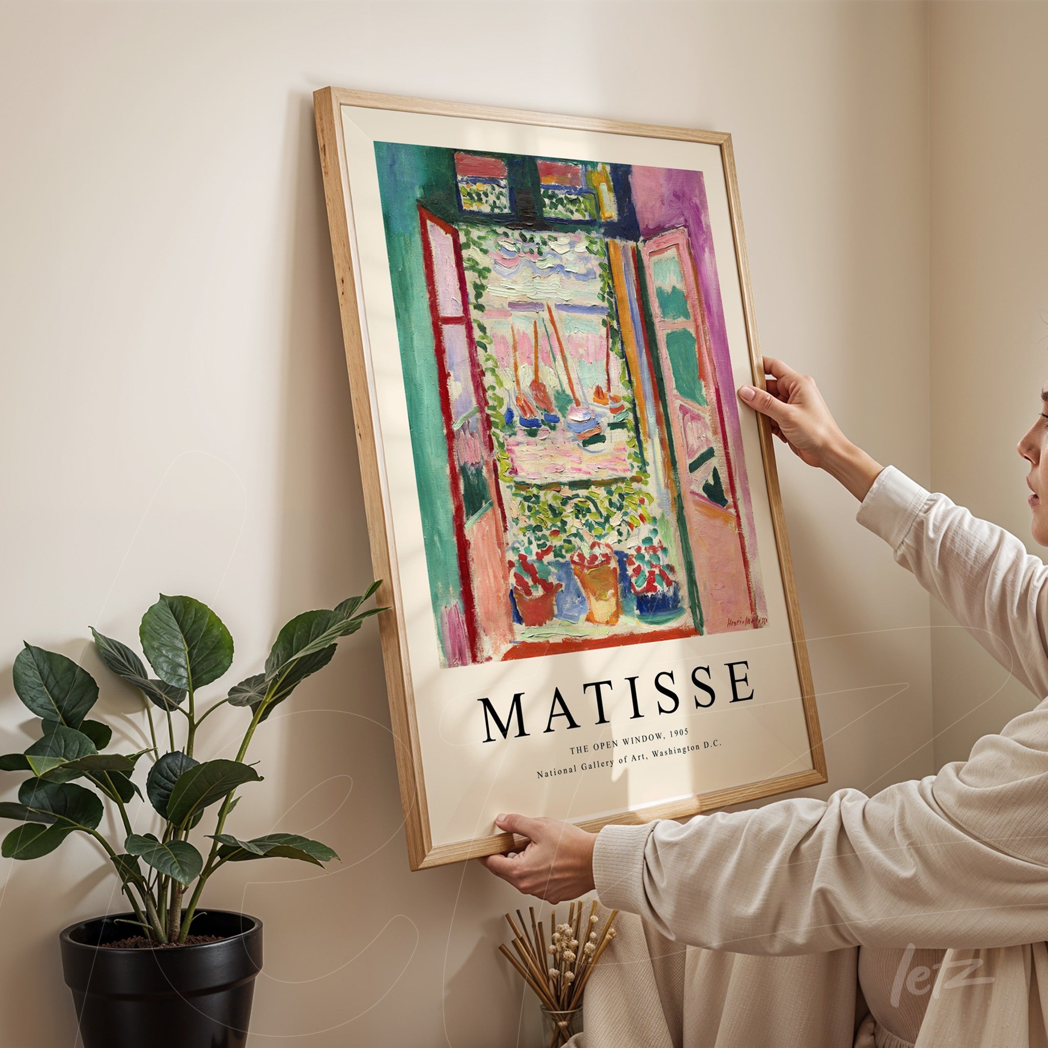 framed artwork by Matisse depicting an open window view of a garden, with light wooden frame
