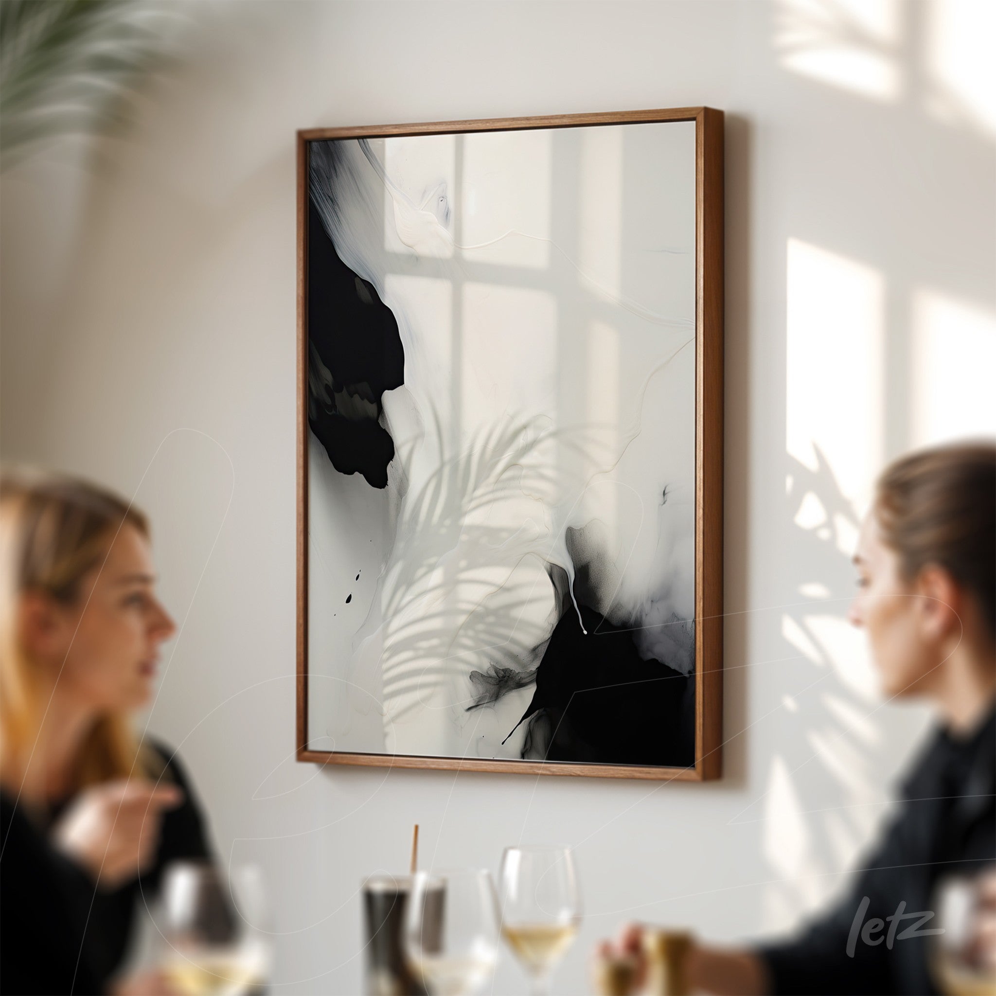 abstract wall art in black and white with light wood frame displayed on a well-lit wall with window shadows
