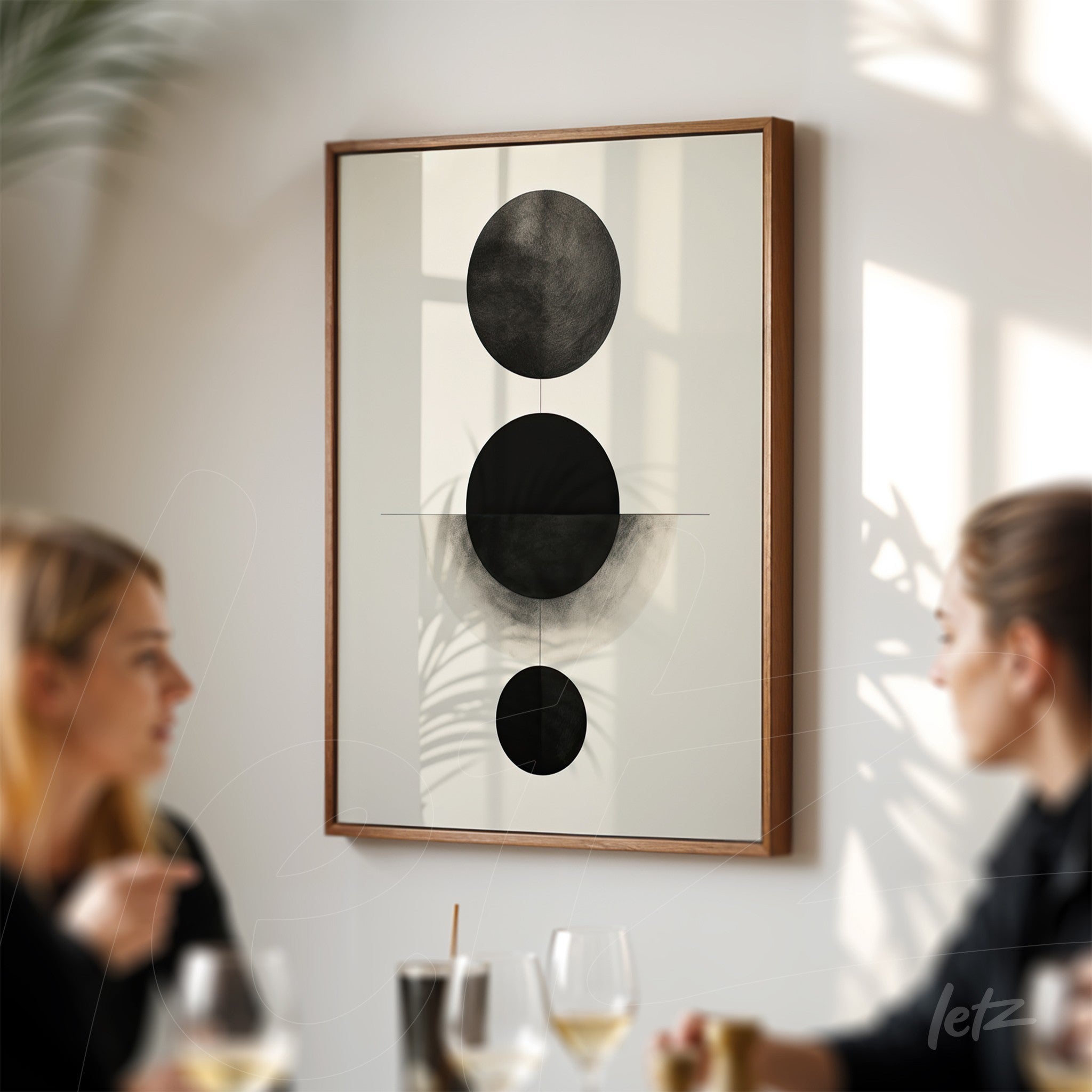 framed abstract black art on light wood display in a softly lit wall context