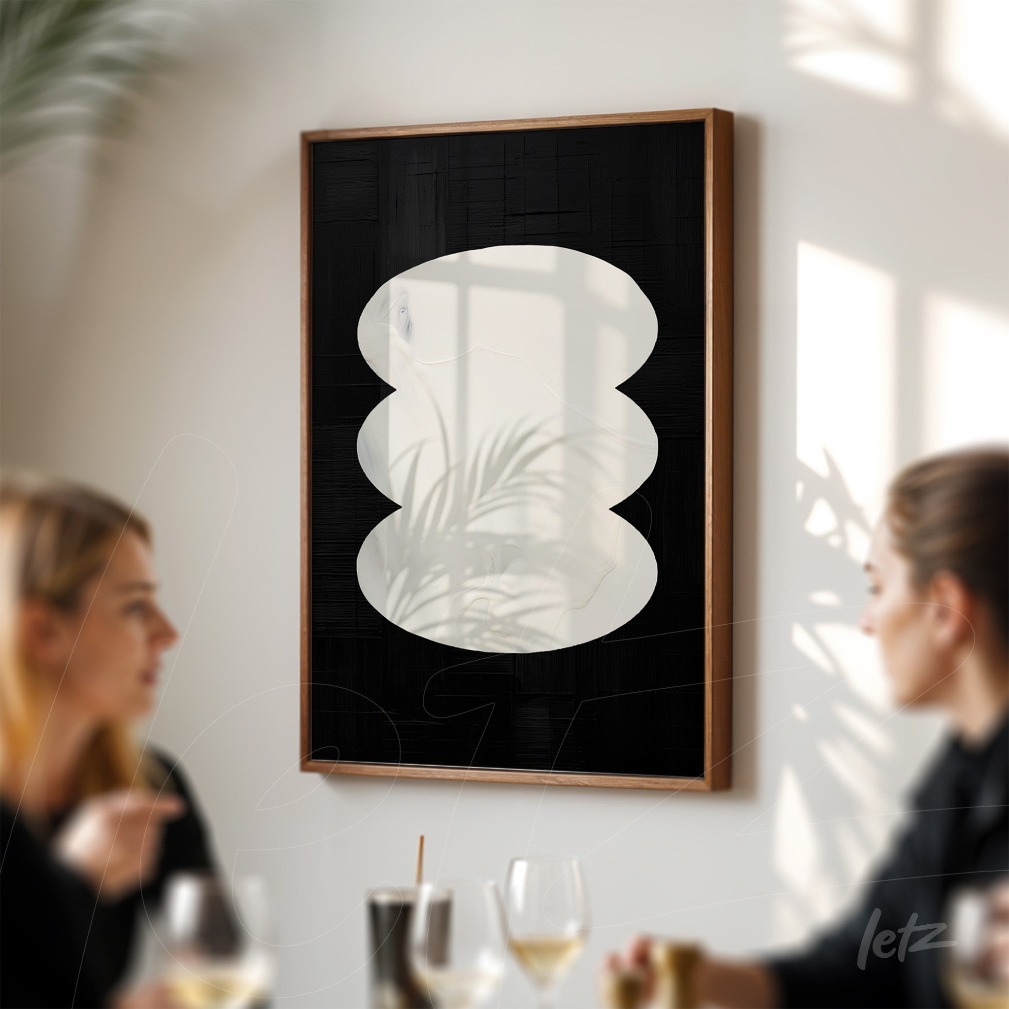 framed abstract art with wavy white shapes on black background, featuring a light wood frame, displayed on a brightly lit wall