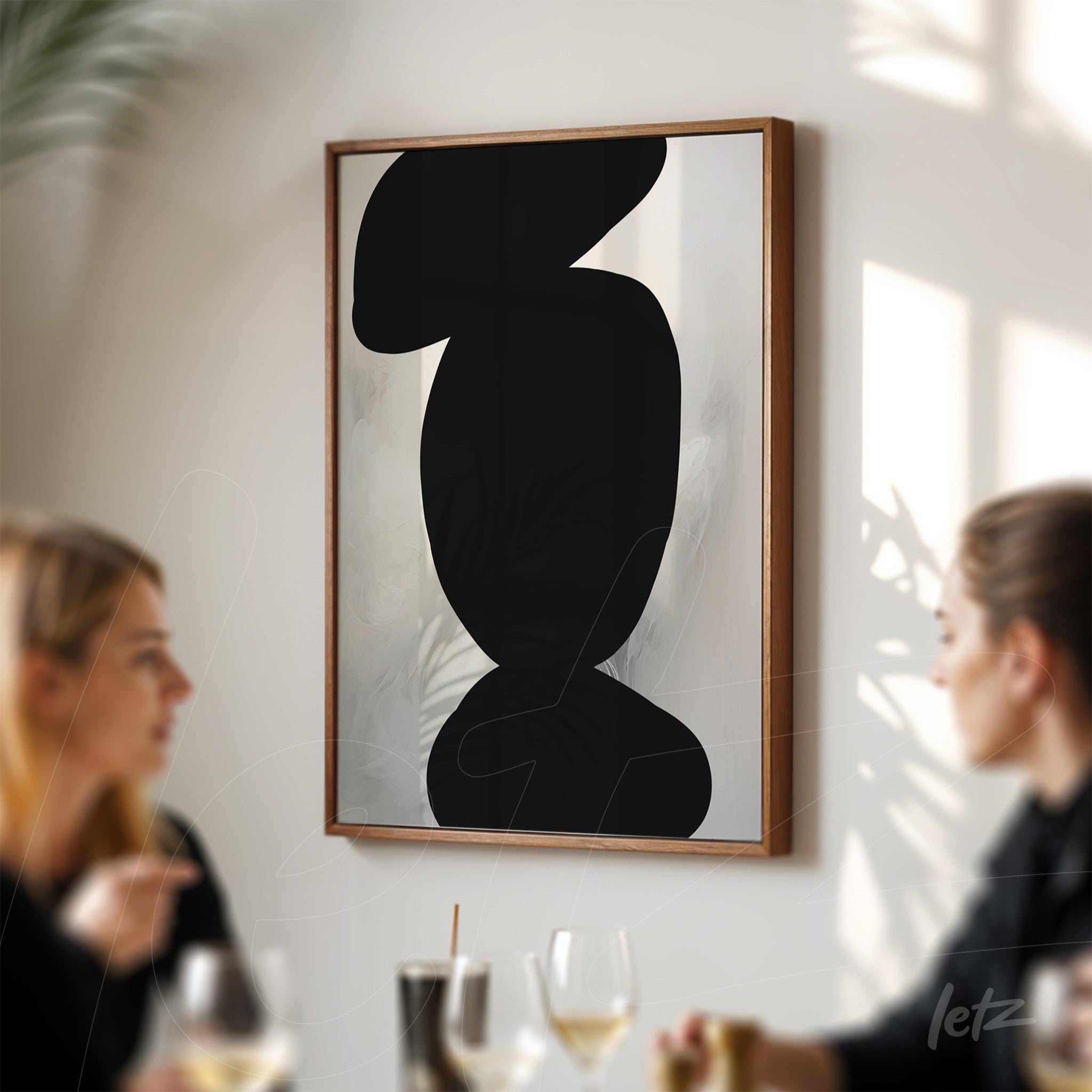 minimalist artwork featuring abstract black shapes on a light background, framed in wood