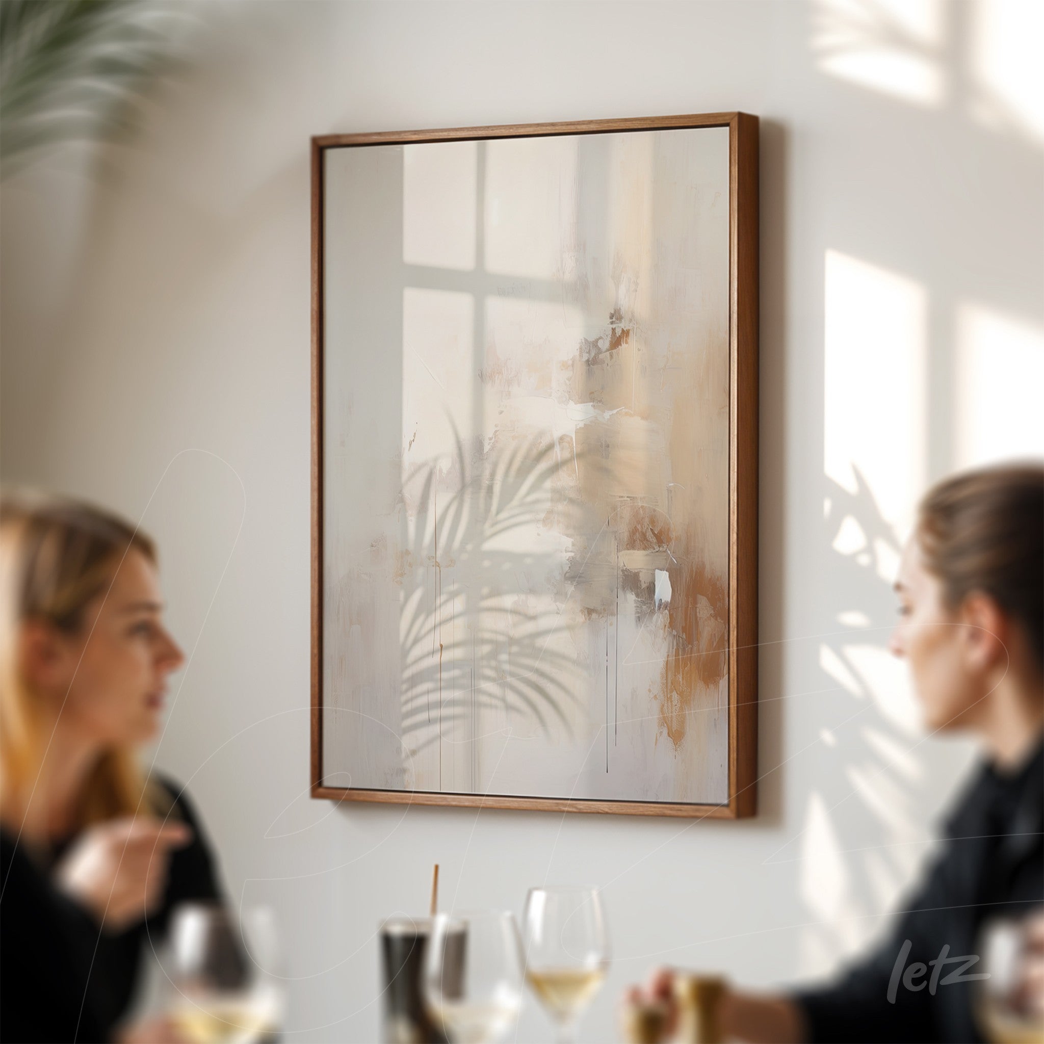 abstract artwork in neutral tones framed in wood displayed on a light wall, reflecting shadows of plants