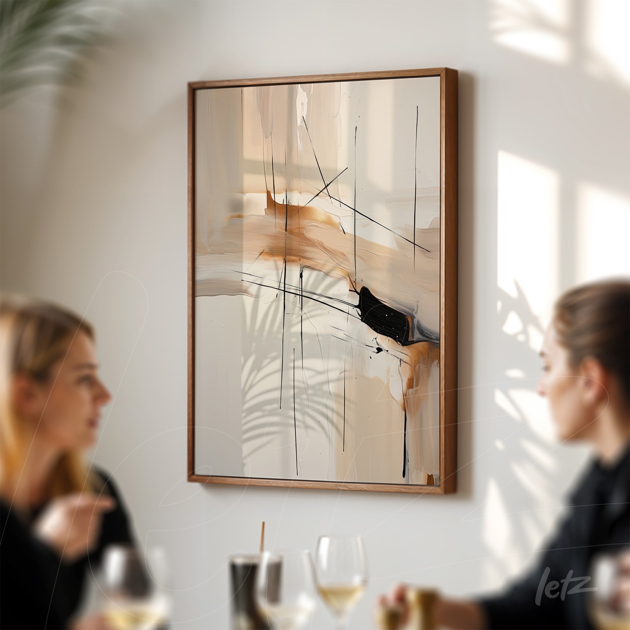 abstract wall art in neutral tones with black lines, framed in light wood, displayed in a setting with two people conversing