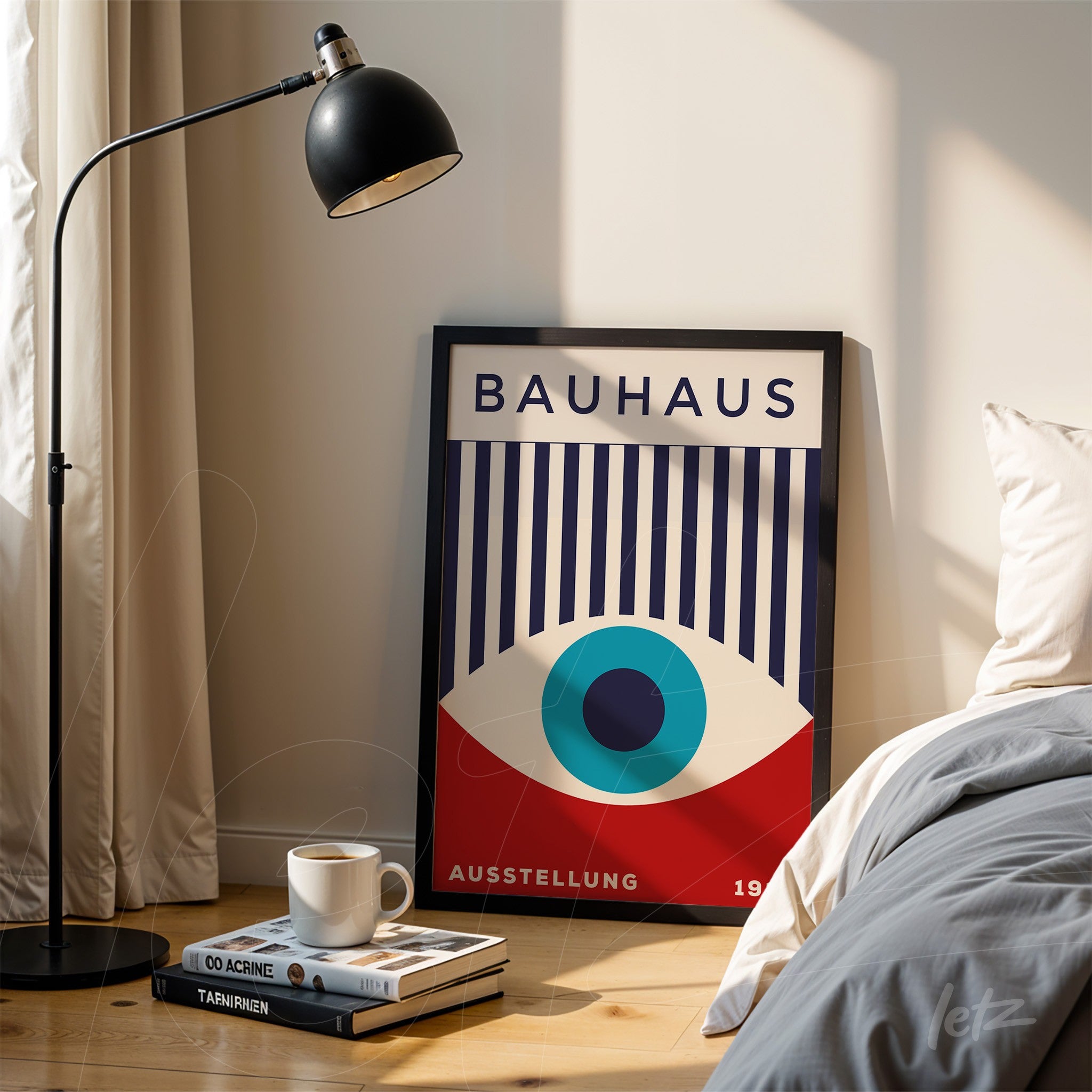 bauhaus poster print in black frame leaning on the floor next to a bed and floor lamp