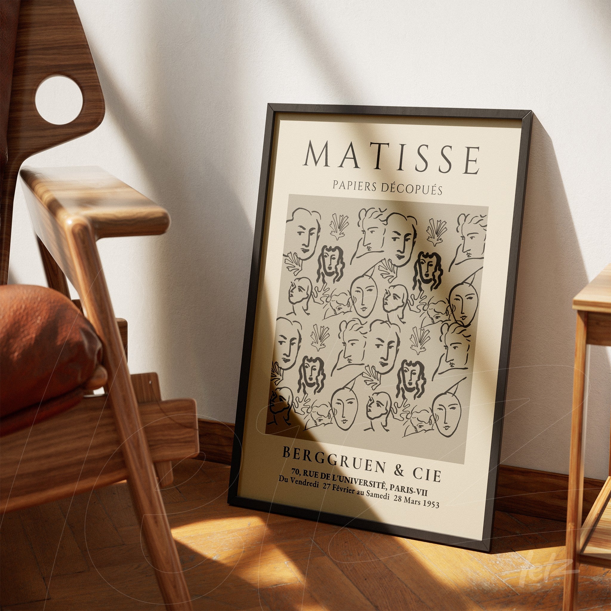 framed vintage style art print featuring abstract faces in black on beige background leaning against the wall