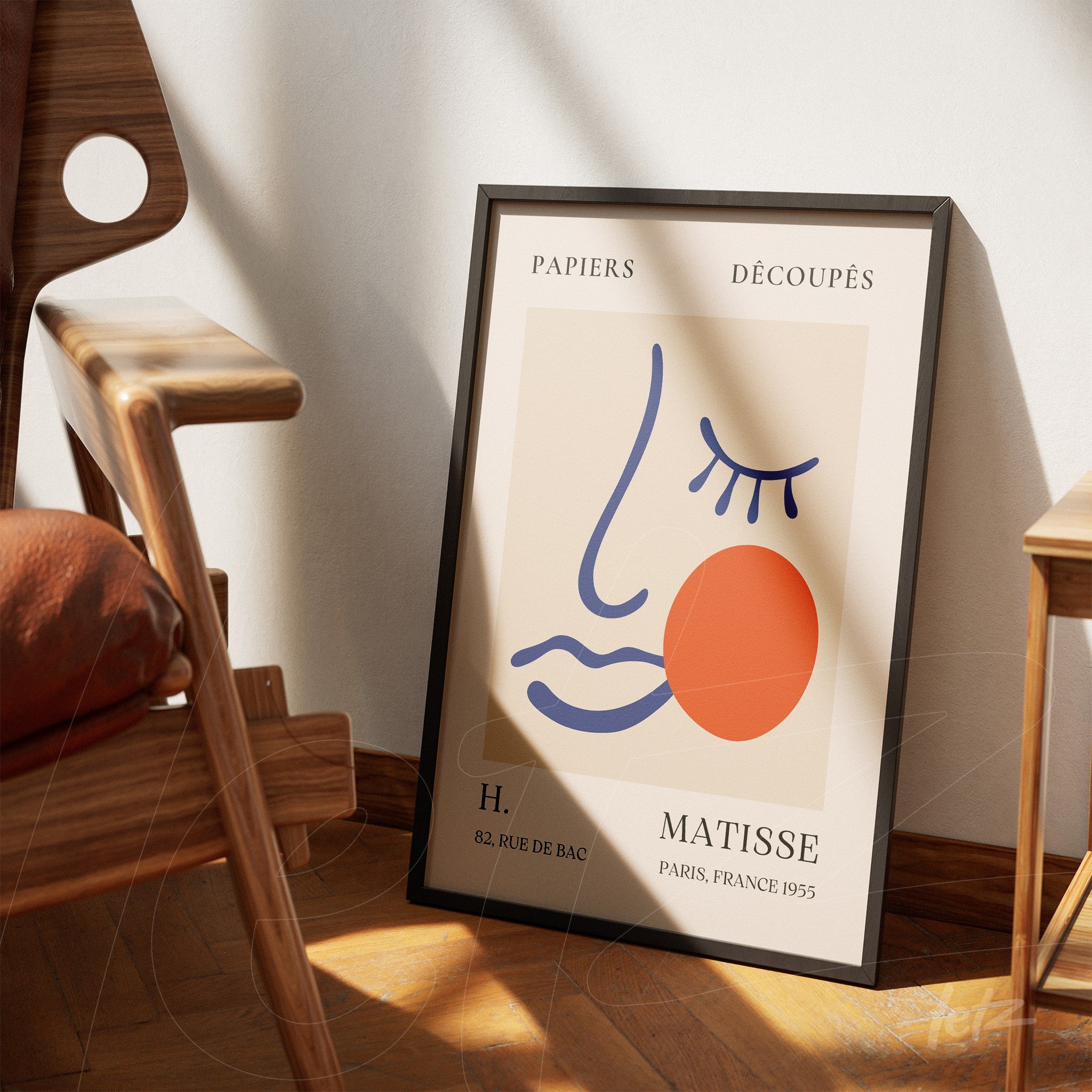 framed decorative art featuring an abstract face in pastel tones, black frame leaning against a wooden chair