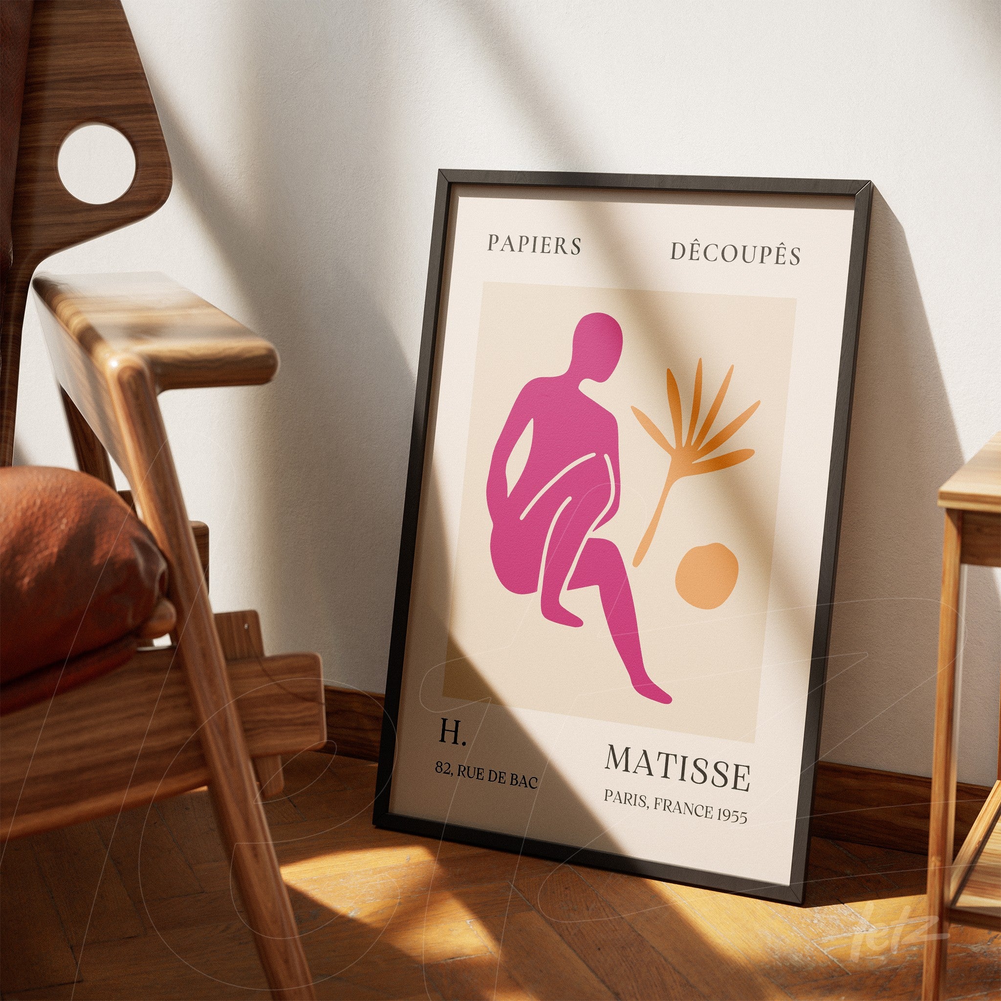 framed wall art featuring a stylized figure in pink and beige tones, displayed next to a wooden chair