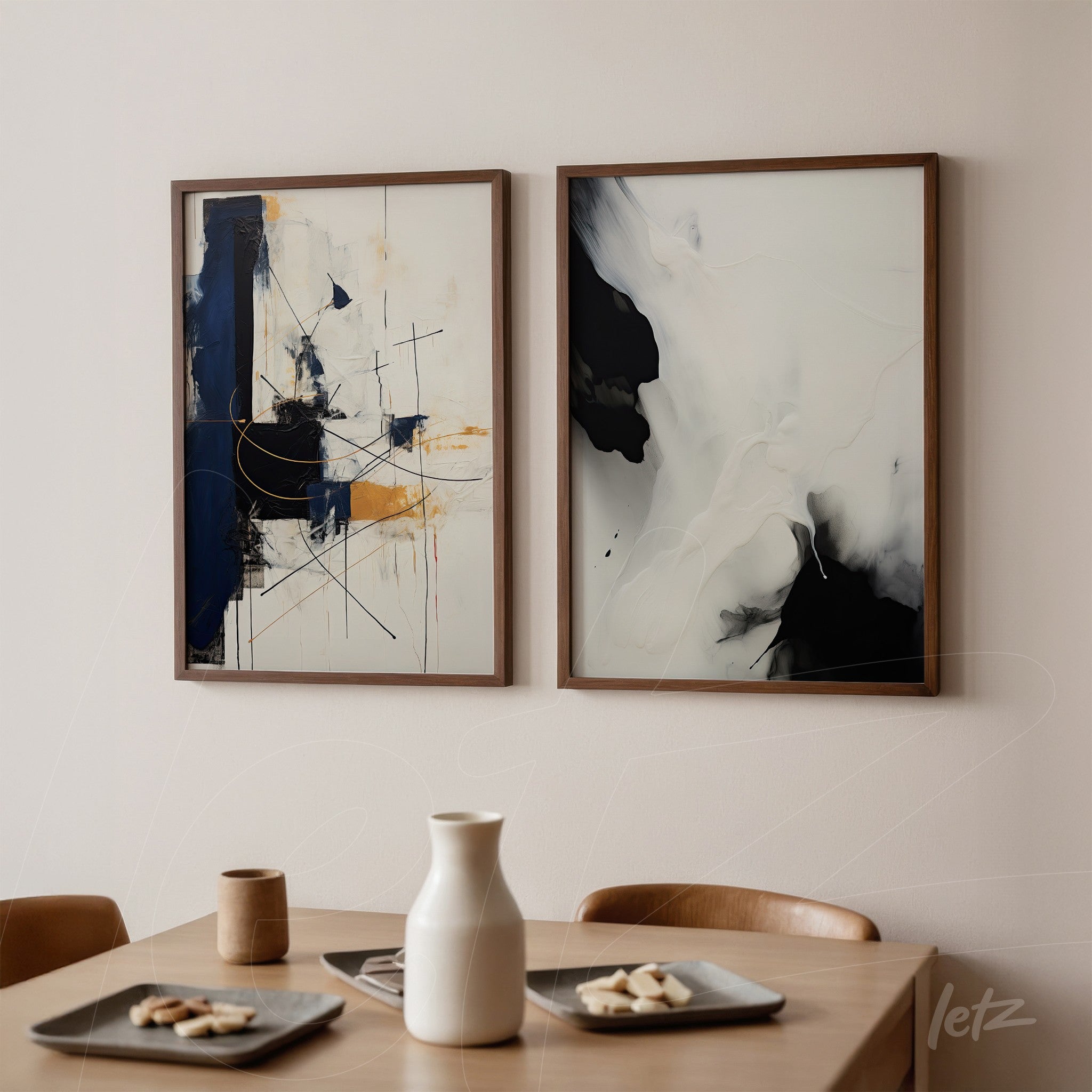 composition of two abstract framed artworks in wooden frames, featuring predominately blue and white tones, displayed on a light wall next to a wooden table with utensils