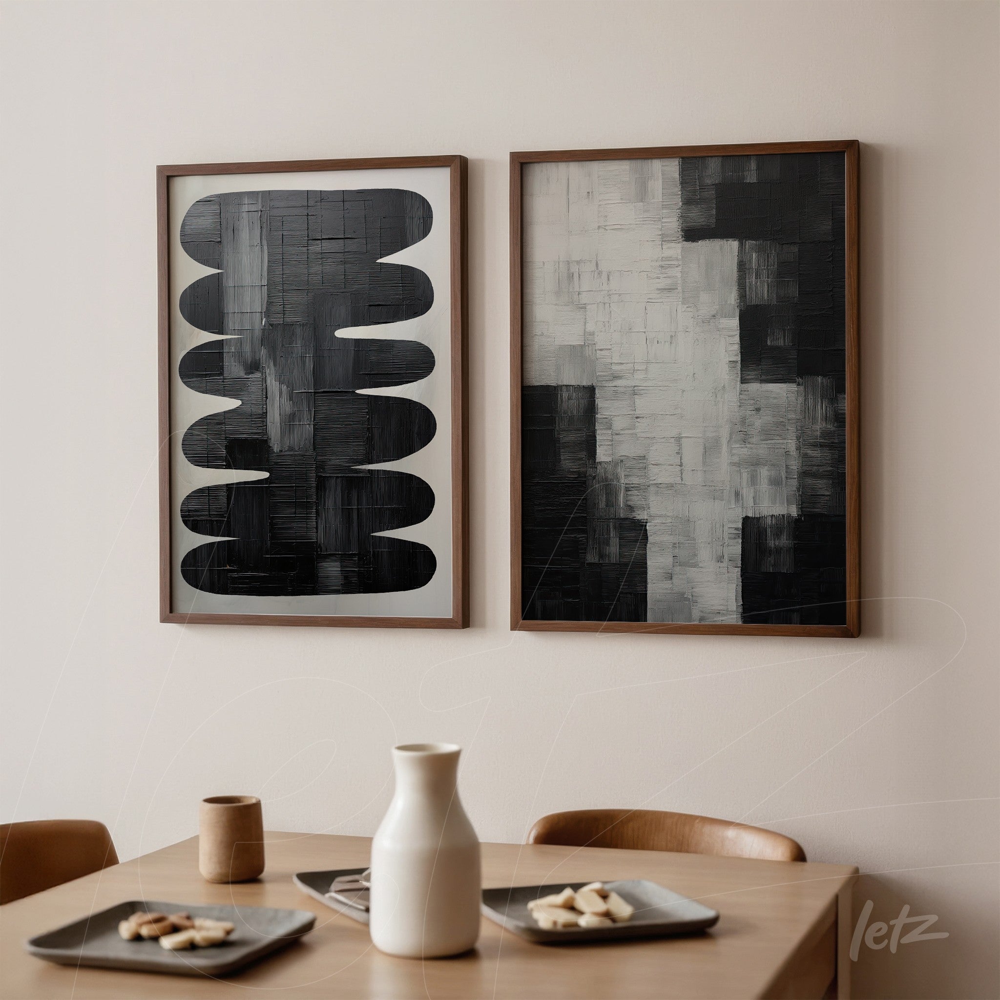 composition of two modern framed artworks with one featuring abstract black shapes on white background and the other in shades of gray and black, displayed on light wall in a minimalist setting