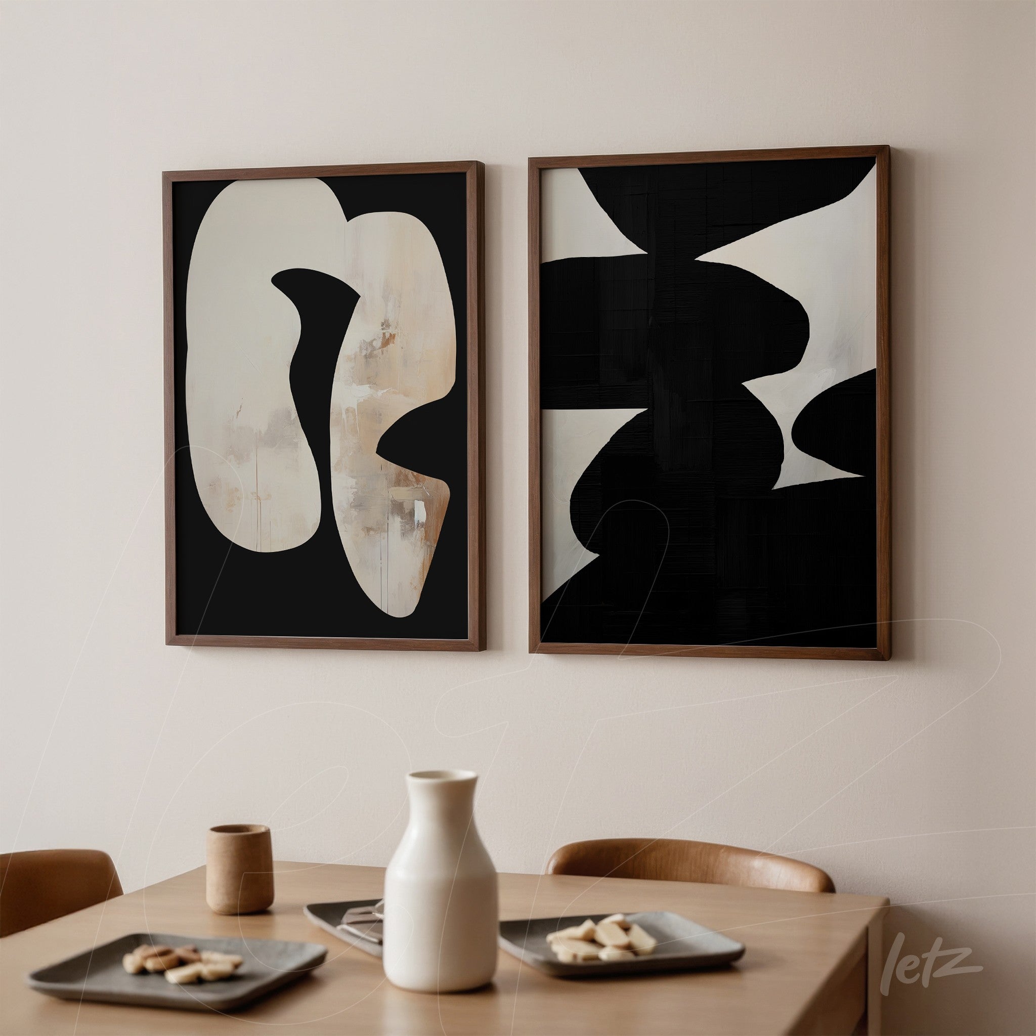 composition of abstract framed artworks in wooden frames featuring black and off-white shapes displayed on a light wall next to a wooden table