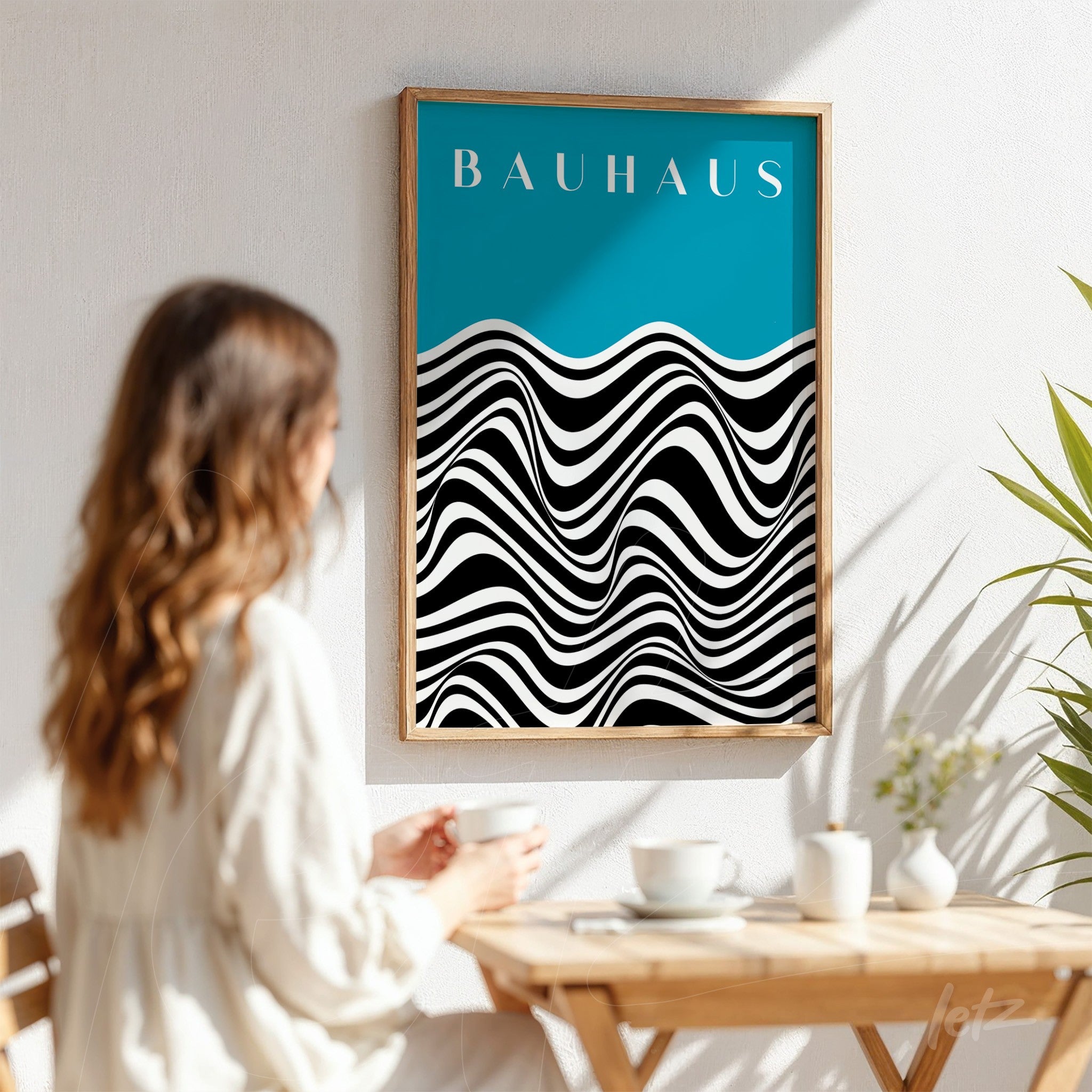 wall decor with black and white abstract wave print against a blue background, framed in light wood, displayed in a bright setting