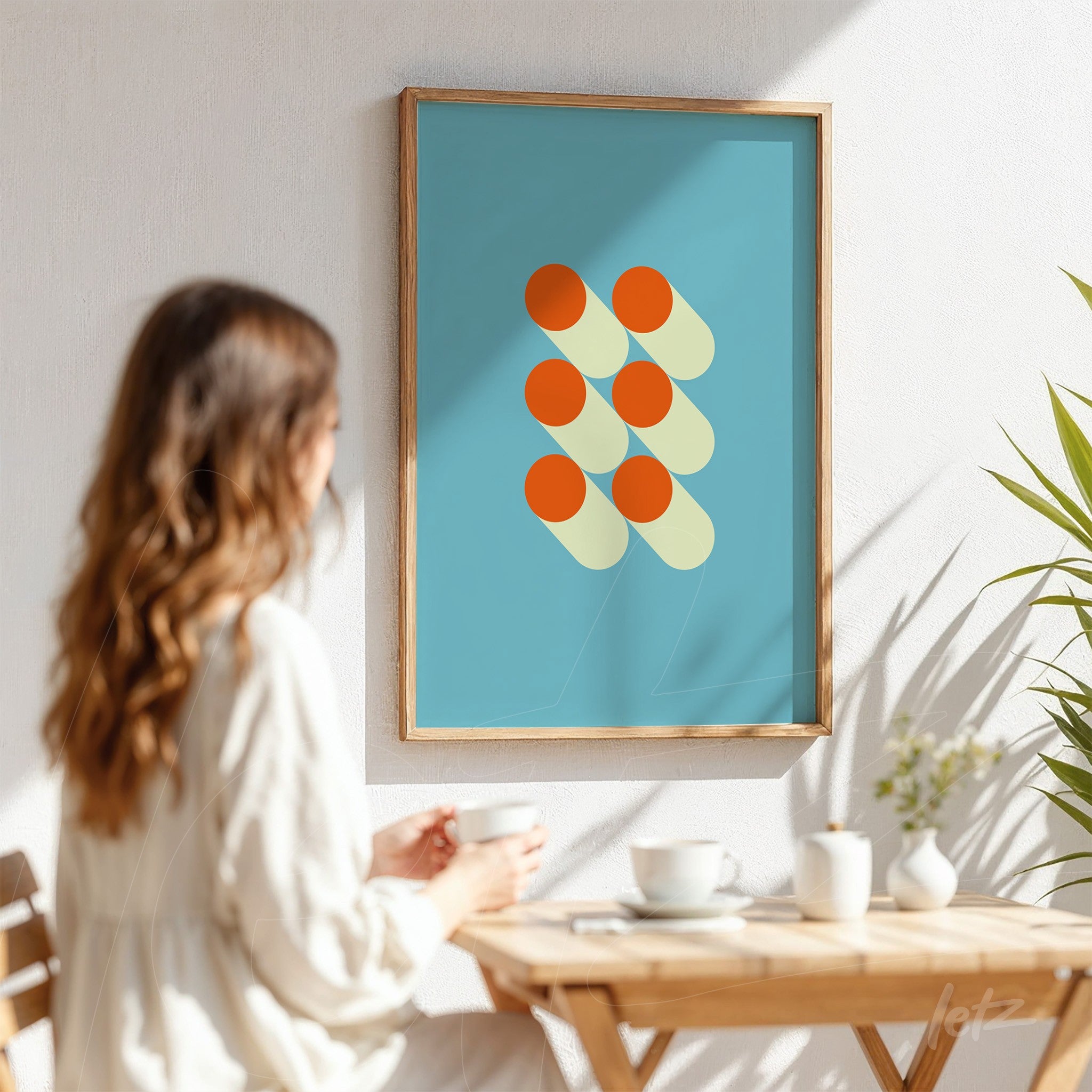 framed geometric art with orange circles on blue background displayed on white wall