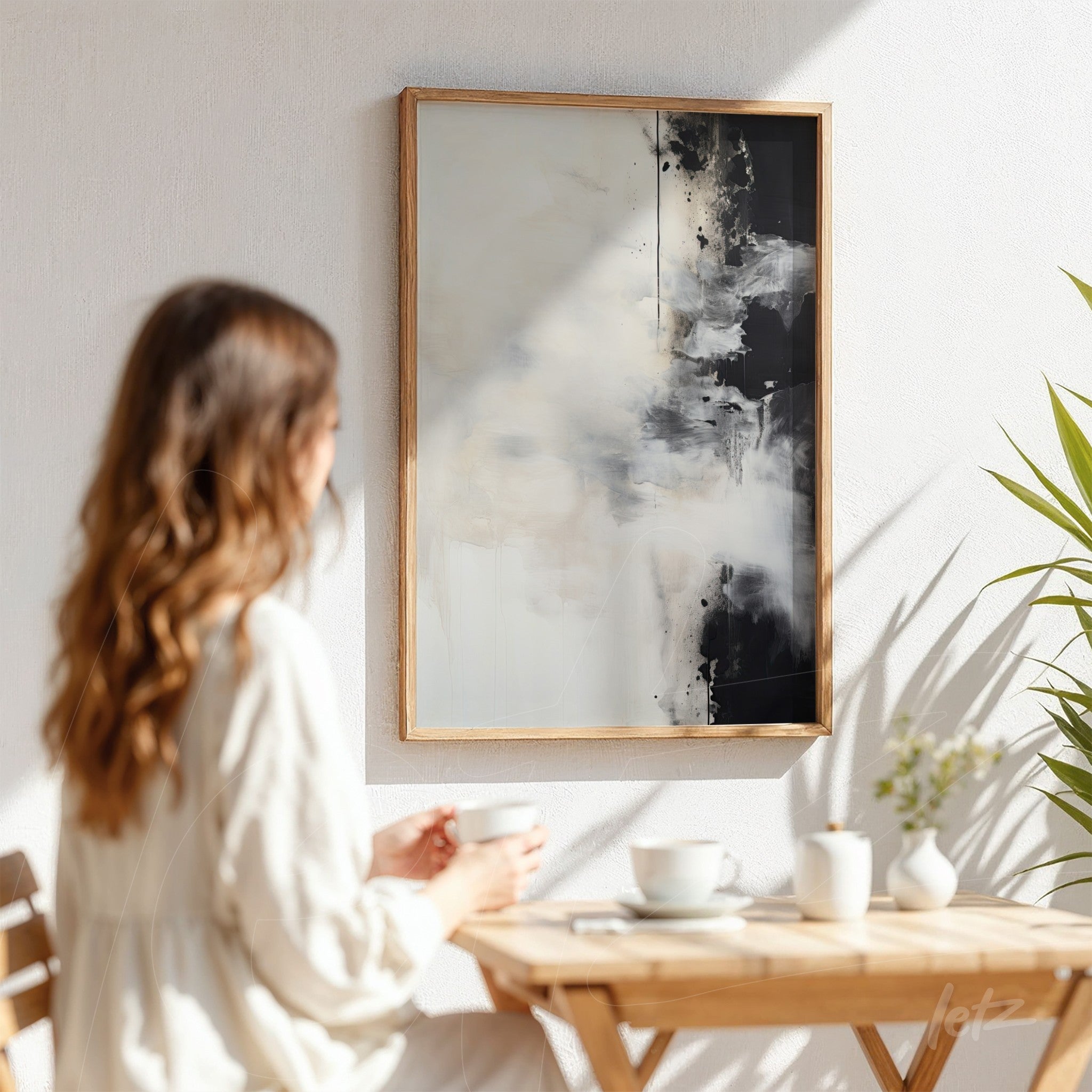 abstract wall art with light and dark tones in light wood frame displayed on white wall with natural light