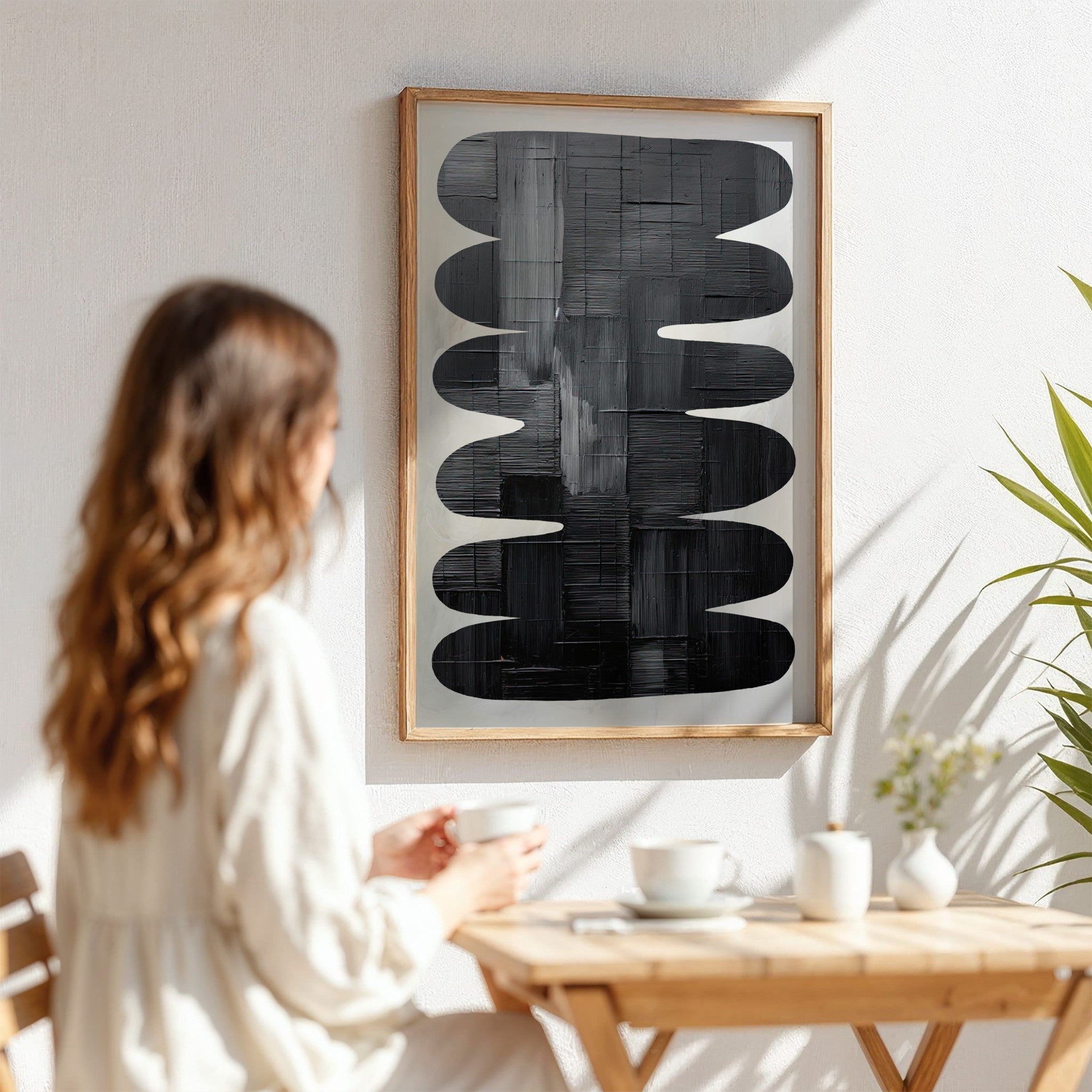 framed abstract wall art in black and white displayed on a sunlit wall with a light wooden frame