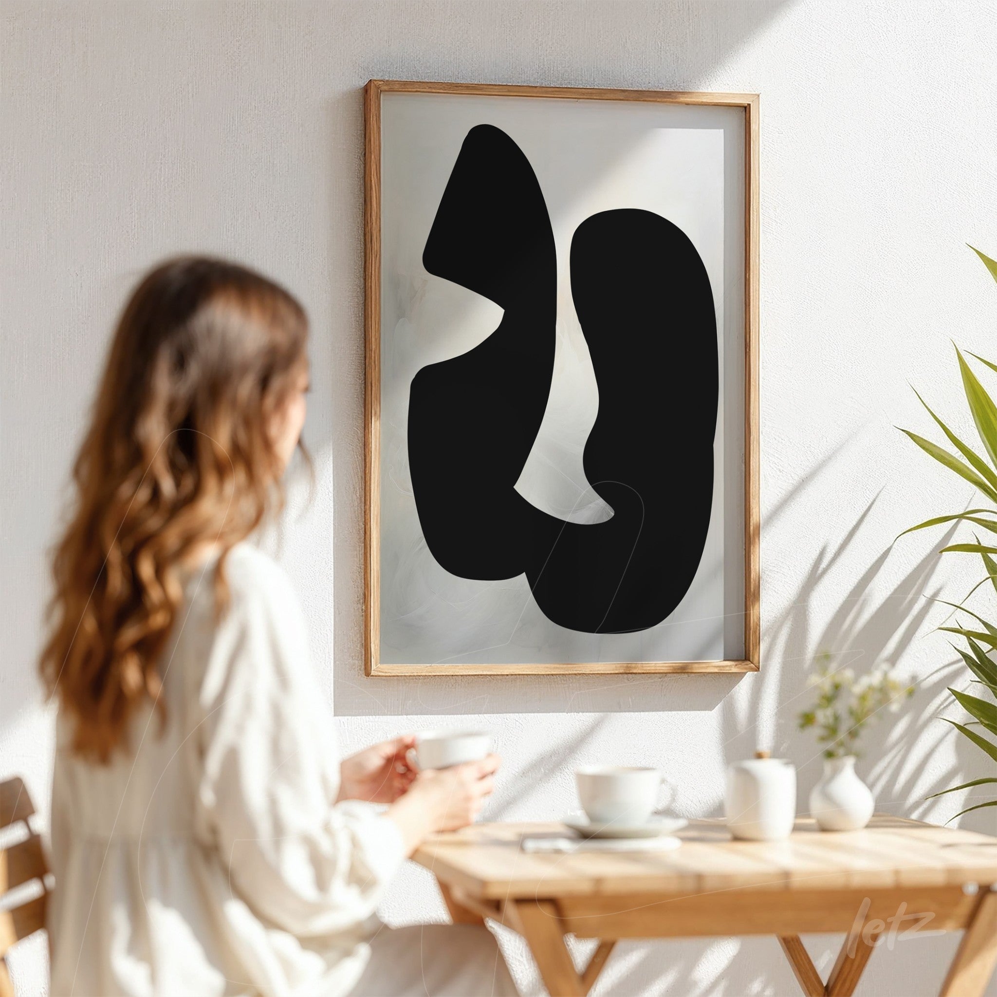 abstract wall art in black featuring organic shapes in a light wood frame, displayed on a white wall