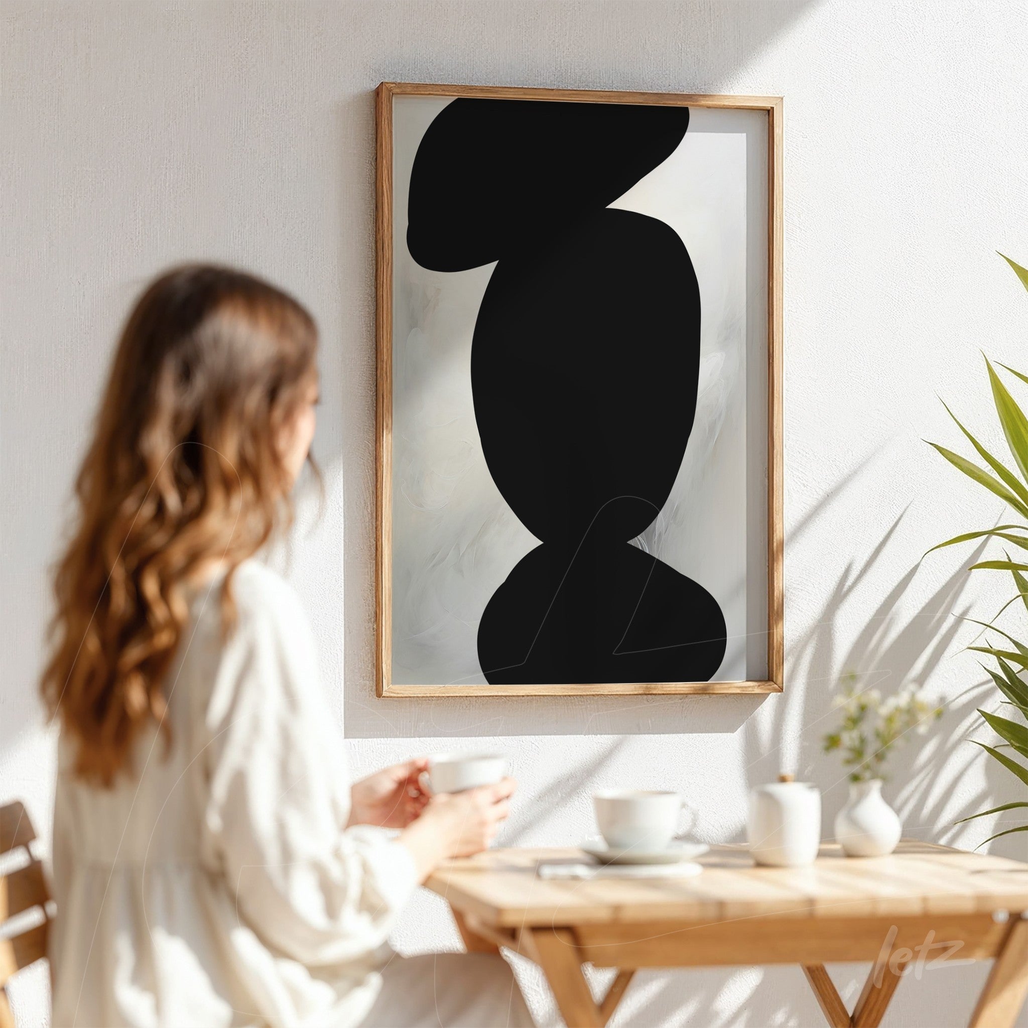 framed abstract art on white background featuring a black silhouette with light wood frame
