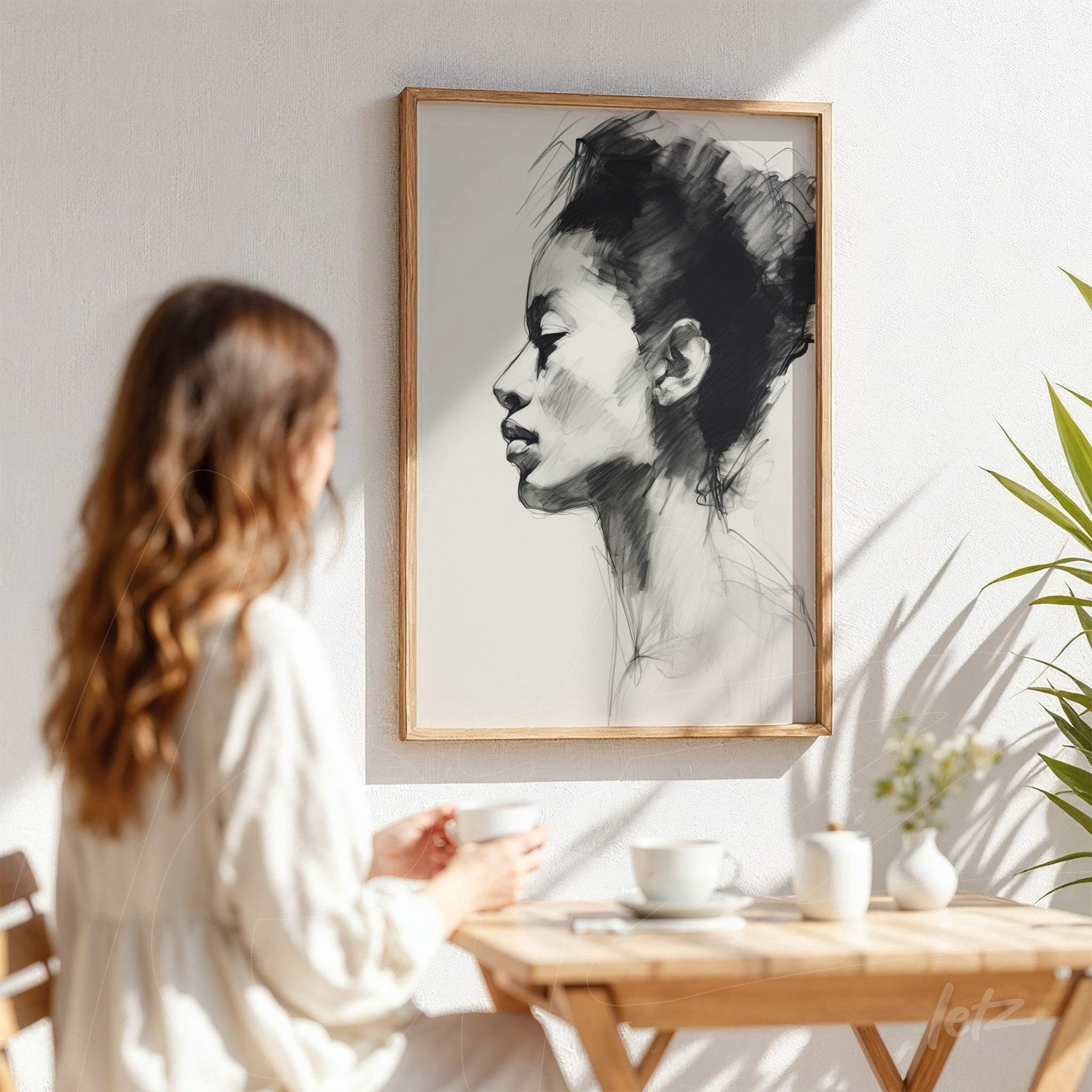 framed minimalistic portrait of a woman's profile in light wood frame displayed on a white wall