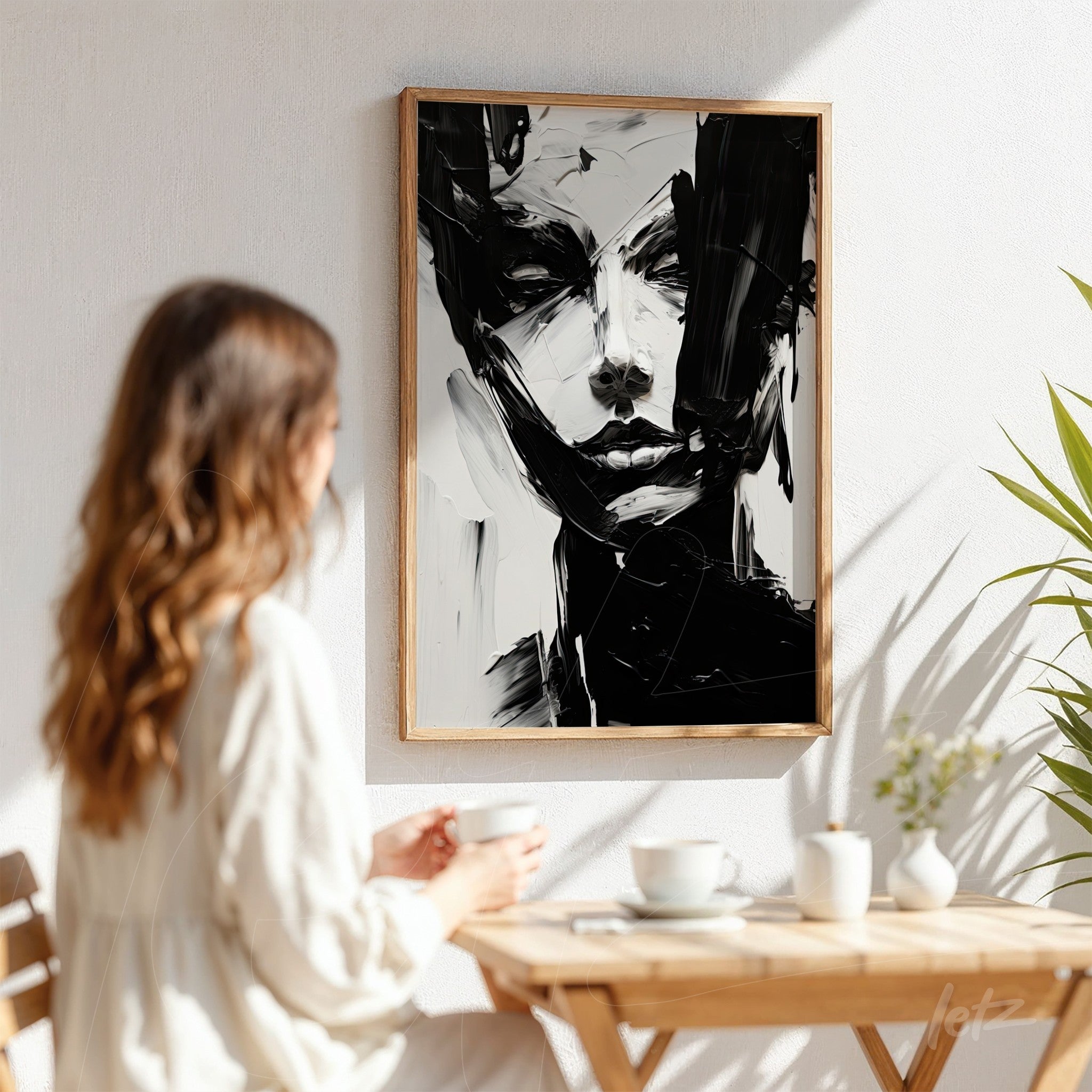 modern black and white artwork featuring an abstract portrait with expressive brushstrokes in a light wood frame displayed on a white wall