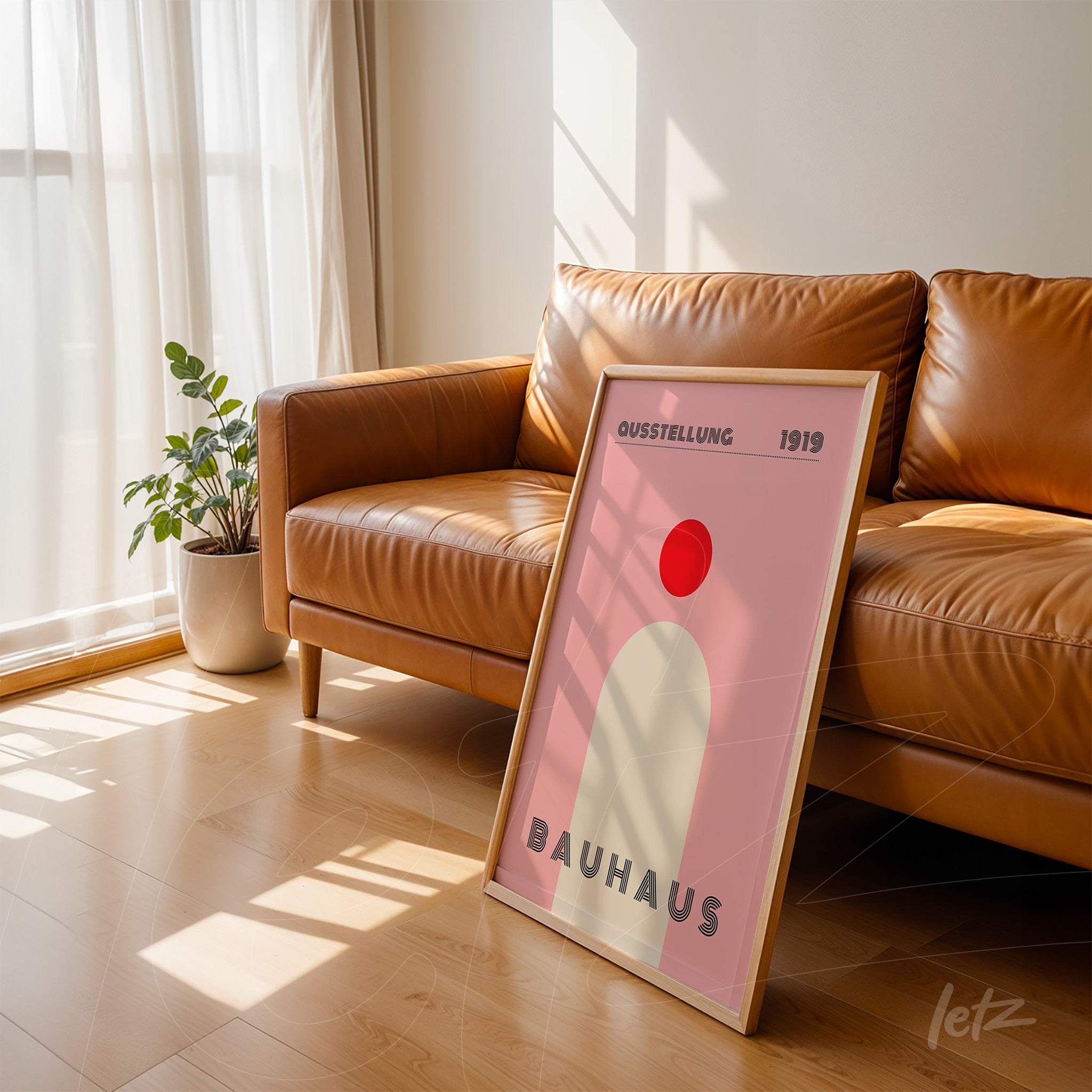poster featuring geometric Bauhaus design in light wood frame, leaning against a brown leather sofa in a well-lit setting
