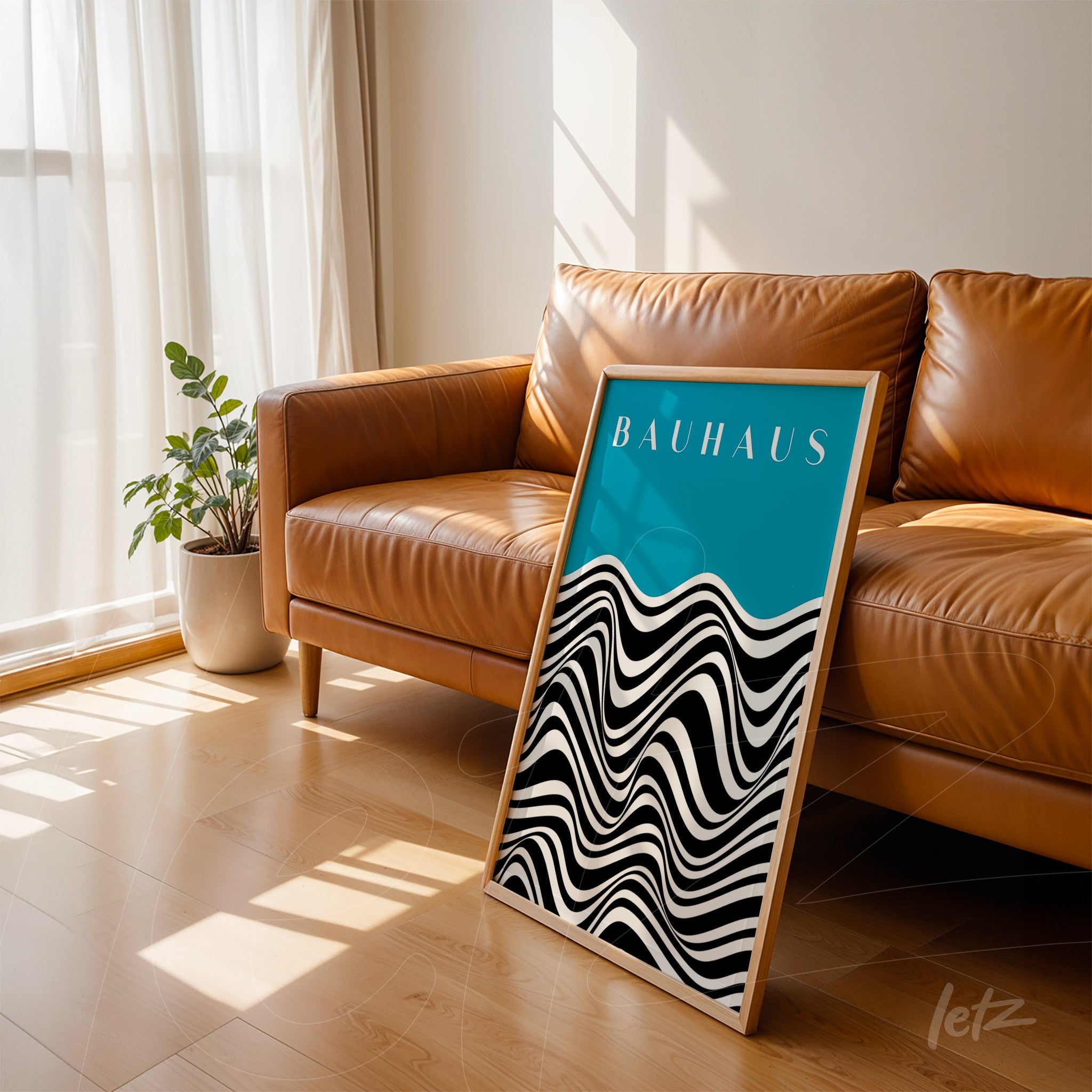 modern framed art with black and white waves, bauhaus text on blue, leaning against brown leather sofa