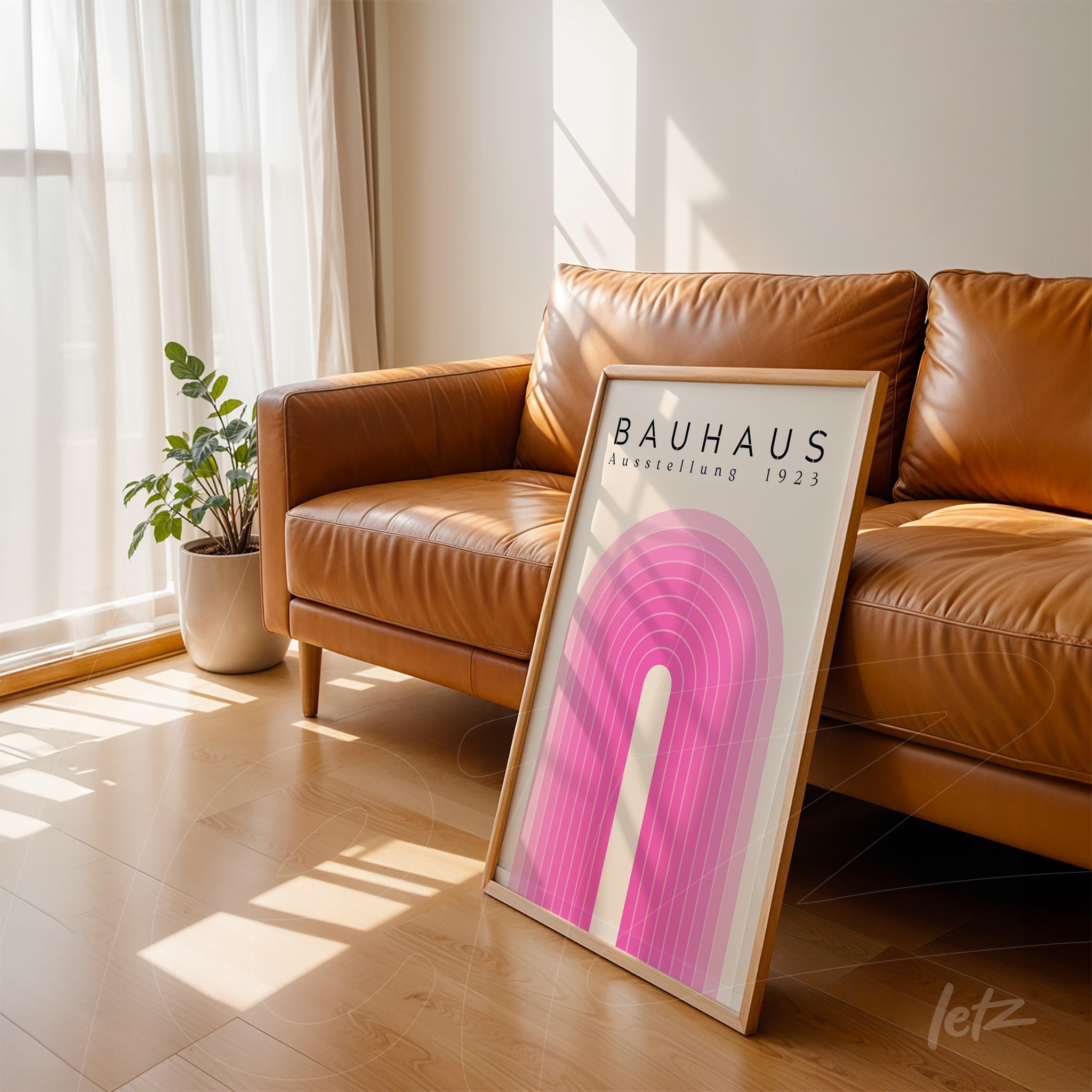 bauhaus style framed art with pink geometric shapes leaning against brown leather sofa