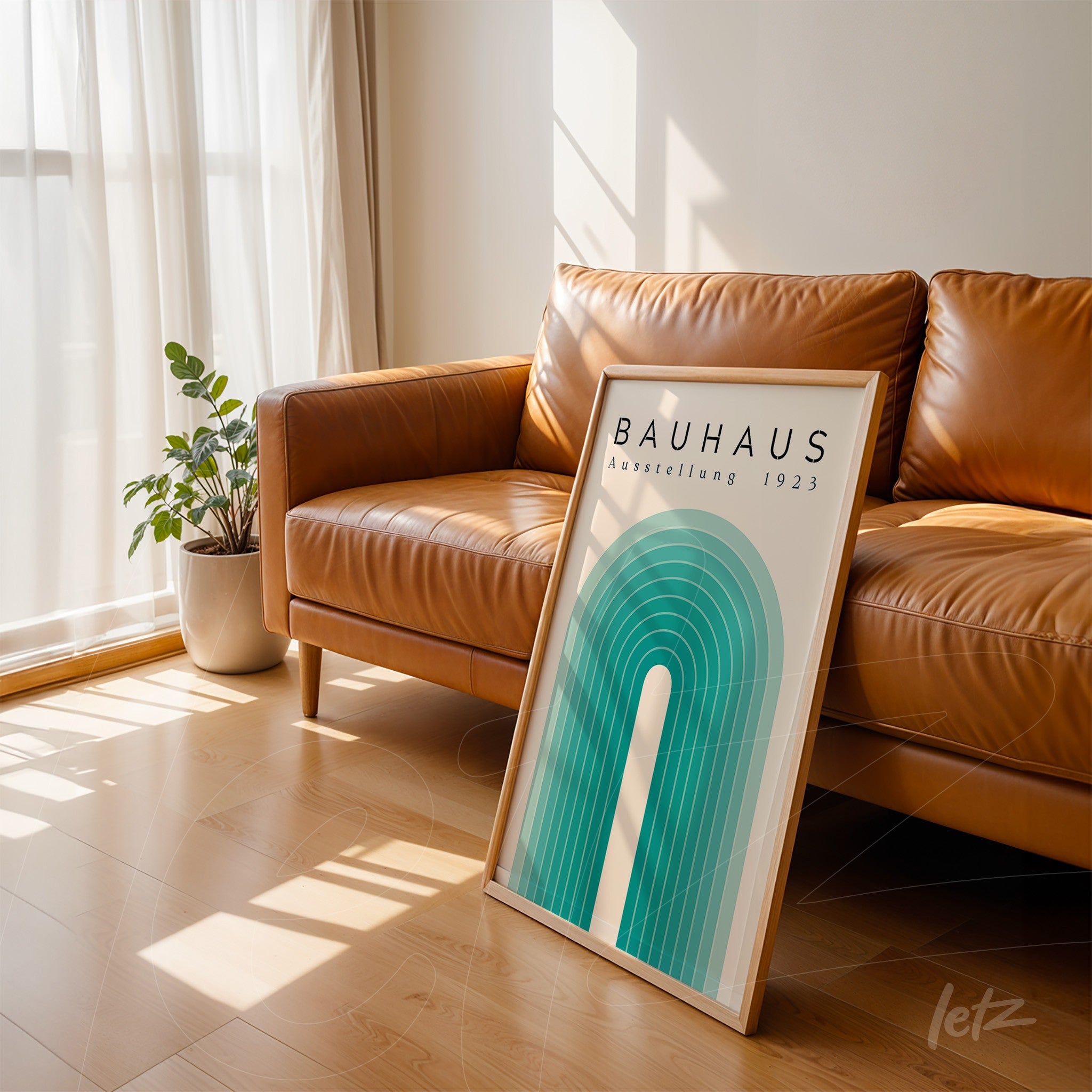 poster with bauhaus design of green and blue arches framed in light wood leaning against brown sofa