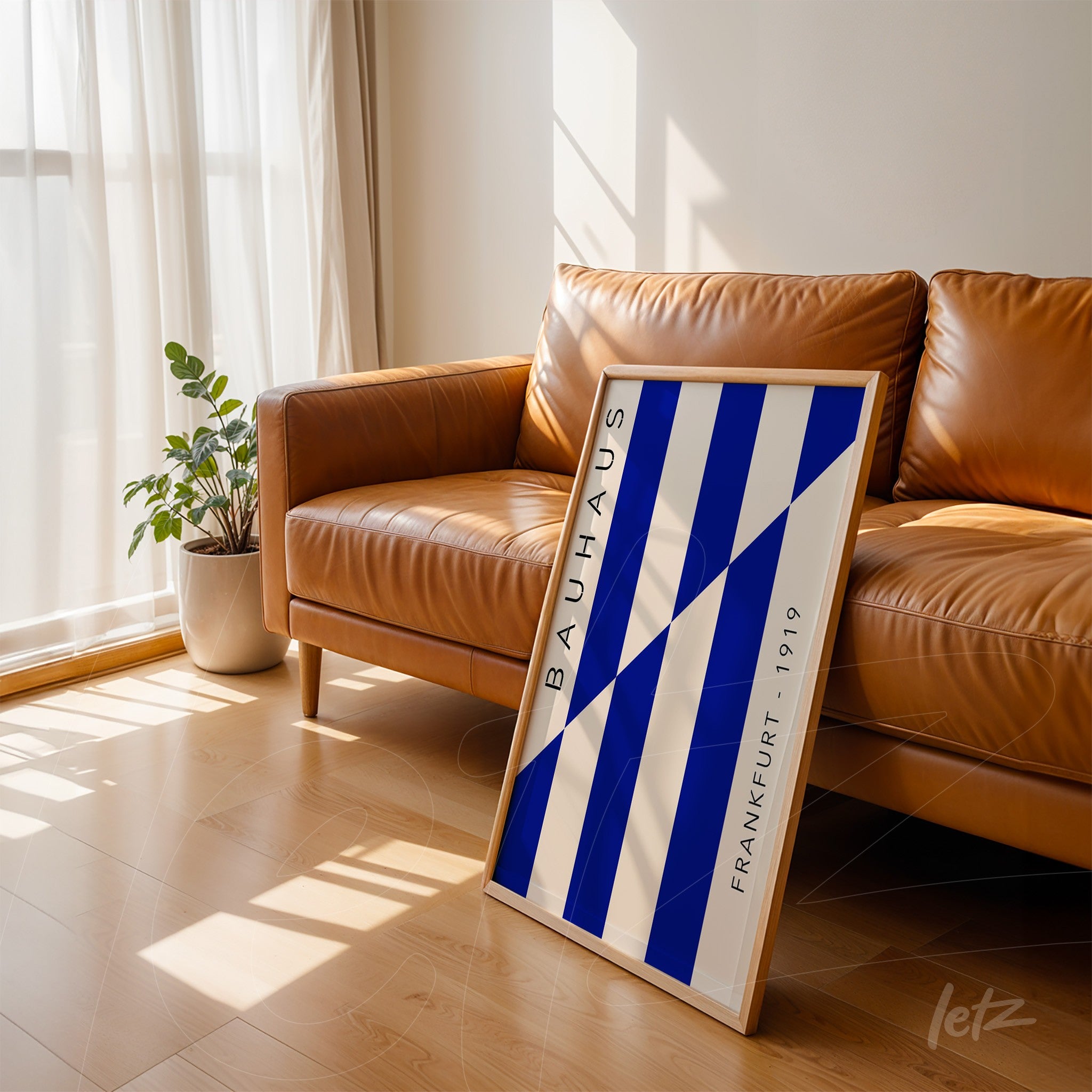 framed geometric wall art in blue and white bauhaus style leaning against brown sofa, light frame