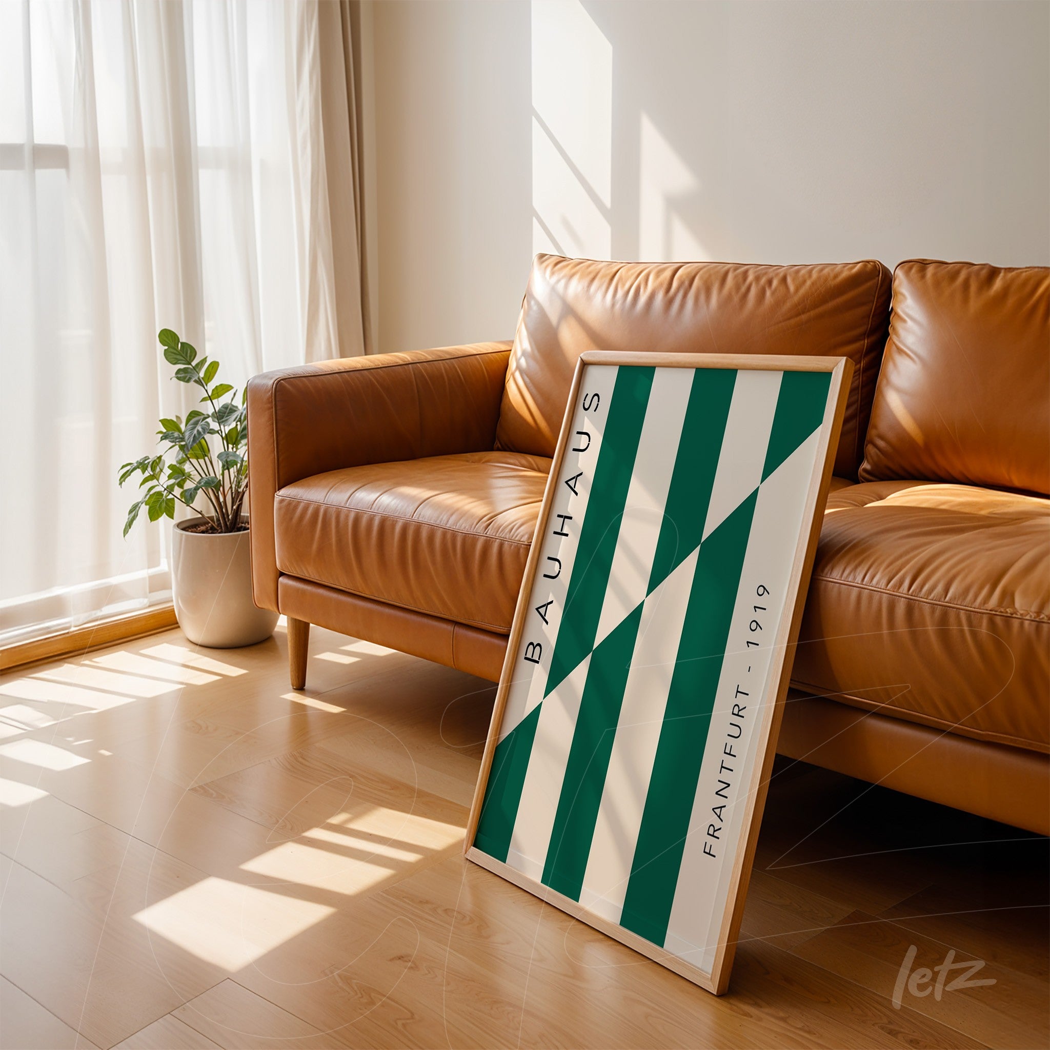 framed art with geometric green and white pattern, labeled bauhaus, leaning on a brown leather sofa